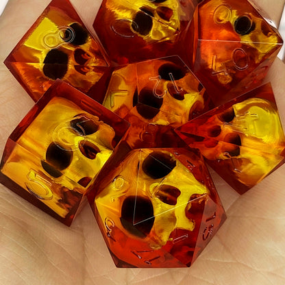 Handmade translucent red resin dice set with embedded skull designs resting in a hand. Gothic RPG polyhedral dice for Dungeons & Dragons and tabletop gaming with dark fantasy aesthetic