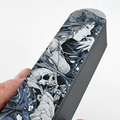 Close-up of a dice box featuring a detailed dark fantasy illustration of a woman surrounded by swirling shadows and skull motifs, shown partially open with RPG dice stored inside, designed by Mefisto_Dice.