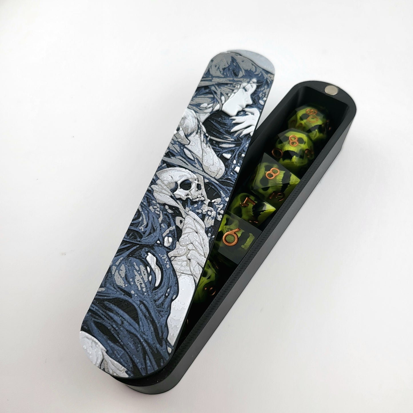 Close-up of a dice box featuring a detailed dark fantasy illustration of a woman surrounded by swirling shadows and skull motifs, shown partially open with RPG dice stored inside, designed by Mefisto_Dice.