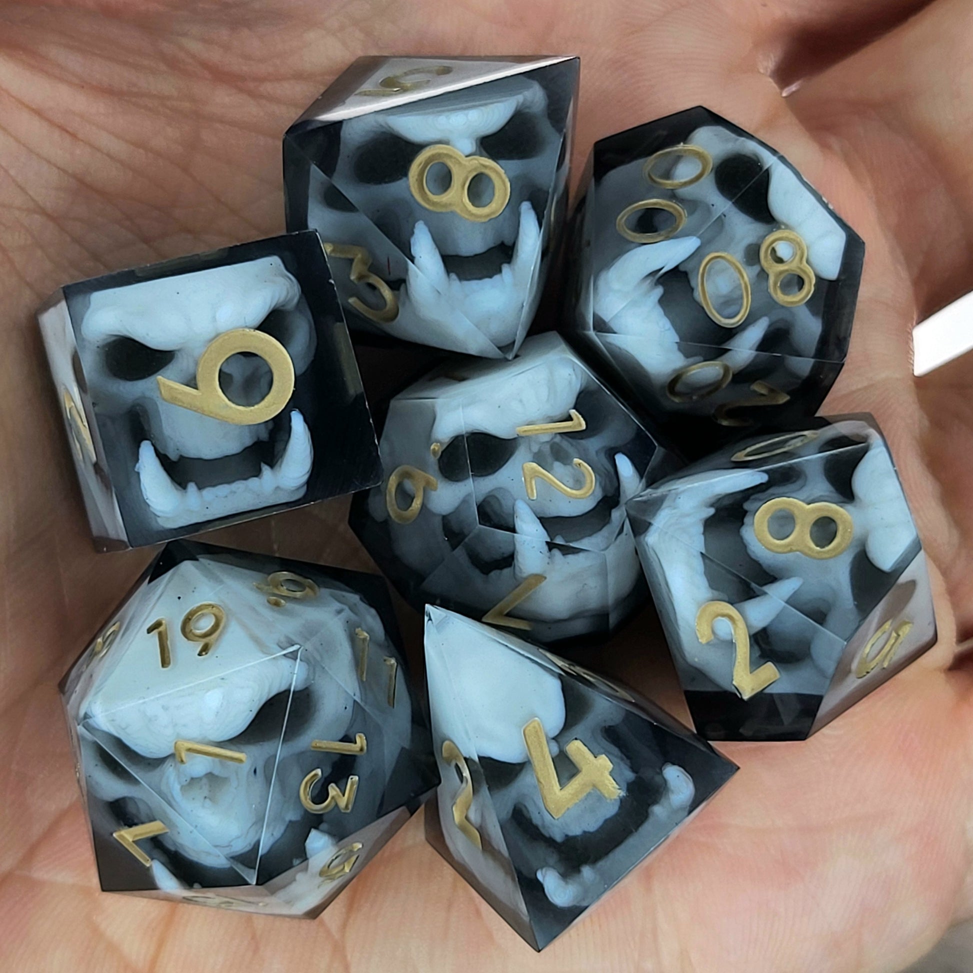 Black and white resin dice set featuring detailed orc skulls with gold numbers, fantasy RPG dice for DnD and tabletop roleplaying games