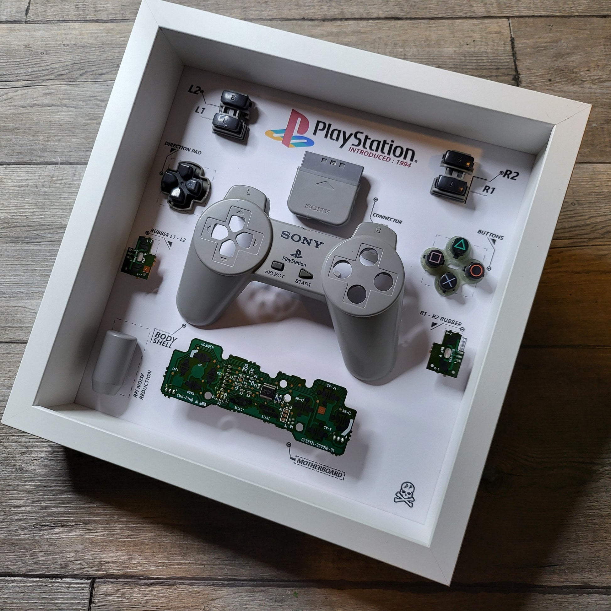 Shadow Box 10x10 with wood frame and polycarbonate glass for wall and Tabletop containing a disassembled controller for Playstation and Nintendo