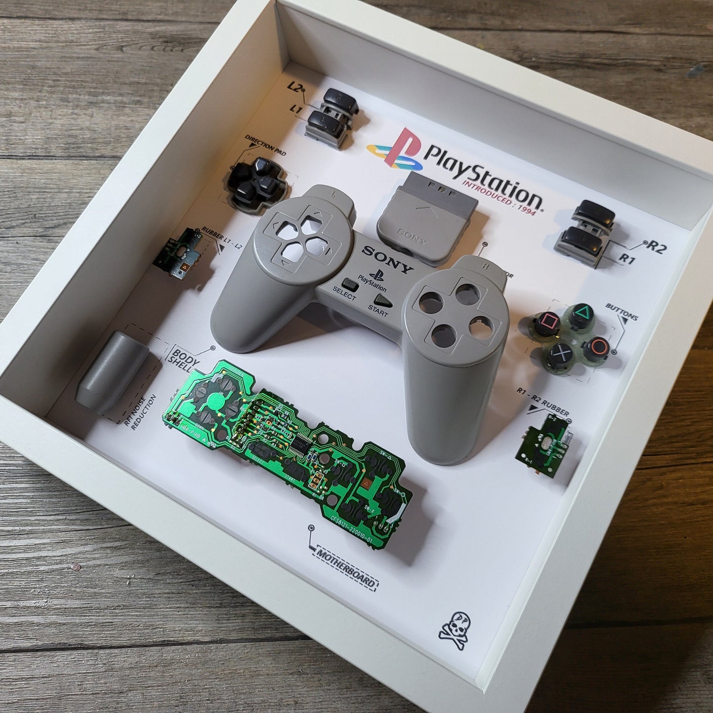 Shadow Box 10x10 with wood frame and polycarbonate glass for wall and Tabletop containing a disassembled controller for Playstation and Nintendo