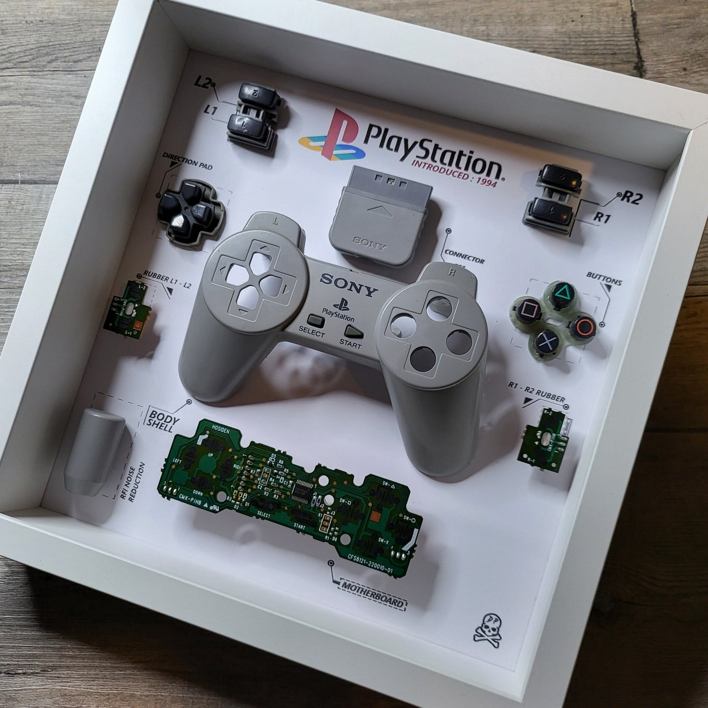 Shadow Box 10x10 with wood frame and polycarbonate glass for wall and Tabletop containing a disassembled controller for Playstation and Nintendo