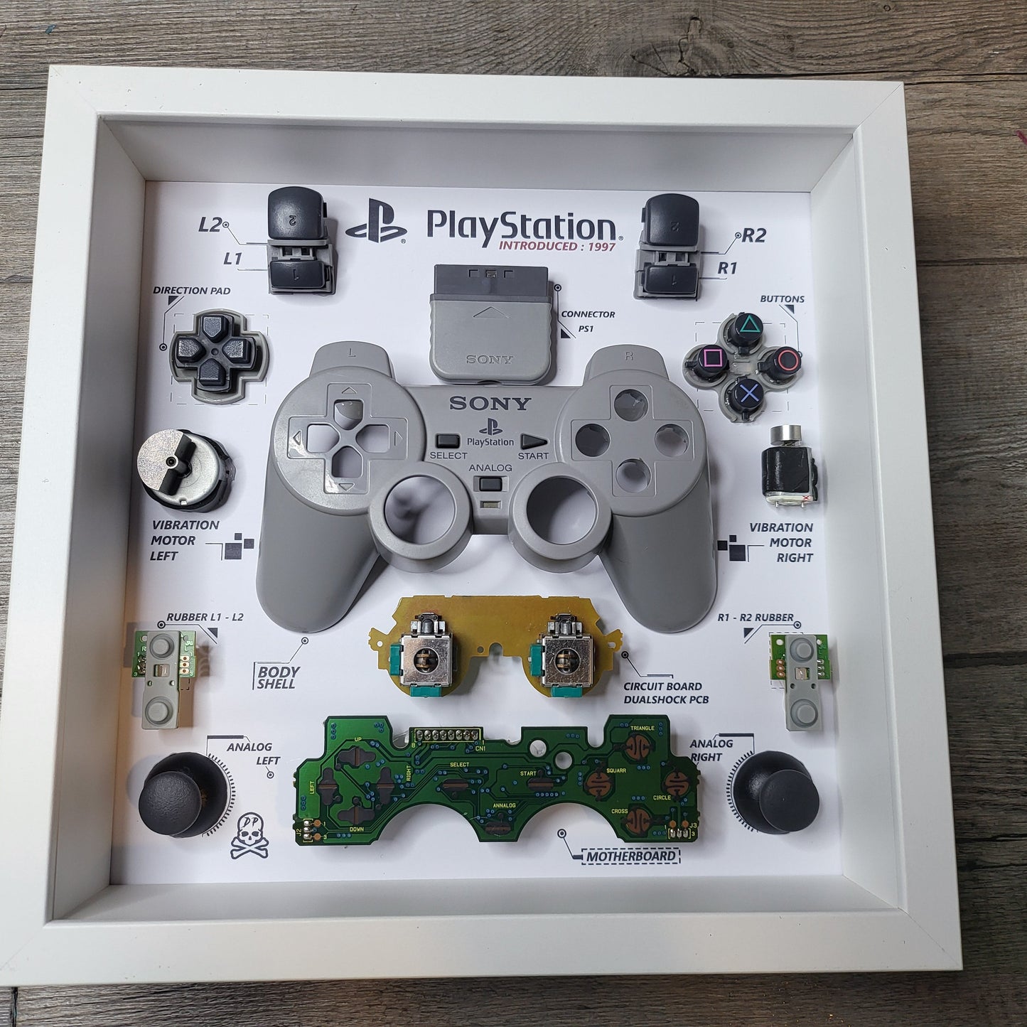 Shadow Box 10x10 with wood frame and polycarbonate glass for wall and Tabletop containing a disassembled controller for Playstation and Nintendo