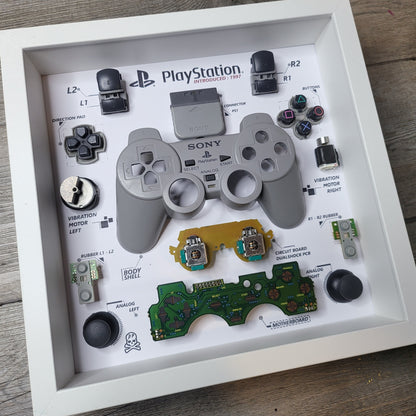 Shadow Box 10x10 with wood frame and polycarbonate glass for wall and Tabletop containing a disassembled controller for Playstation and Nintendo