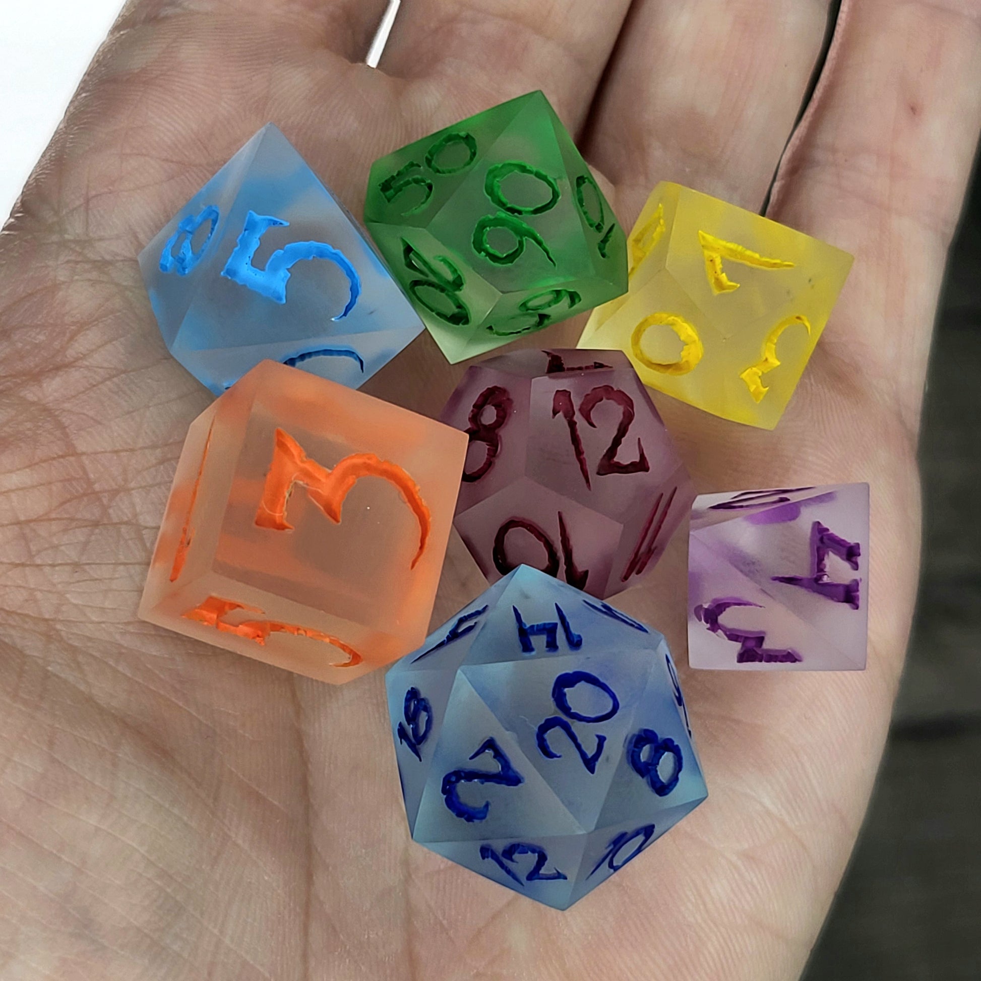 Multicolor frosted resin DnD dice set with matte finish in blue, green, yellow, orange, purple, and red tones