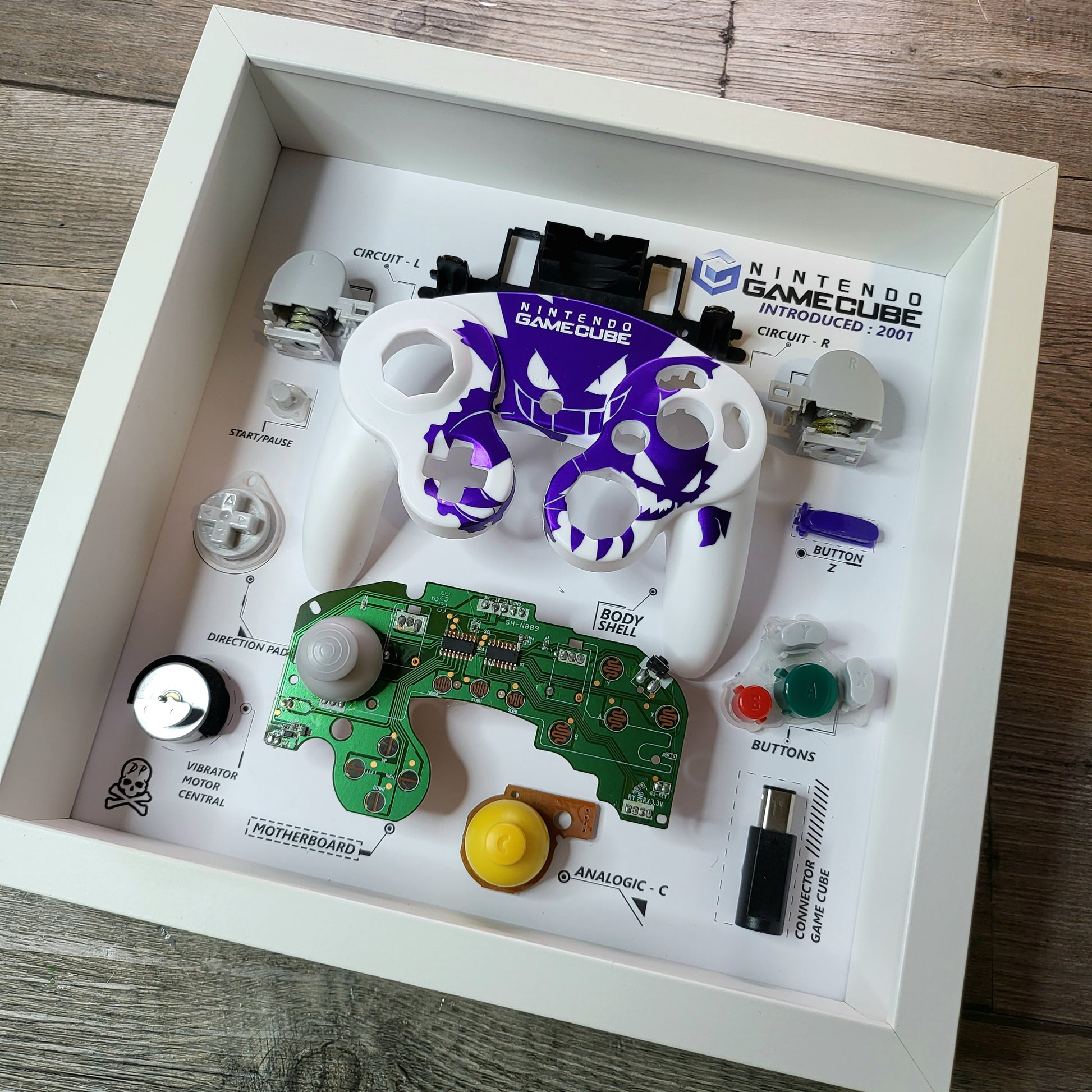 Shadow Box 10x10 with wood frame and polycarbonate glass for wall and Tabletop containing a disassembled controller for Playstation and Nintendo