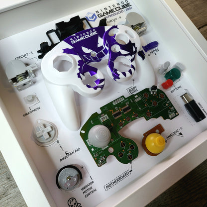Shadow Box 10x10 with wood frame and polycarbonate glass for wall and Tabletop containing a disassembled controller for Playstation and Nintendo