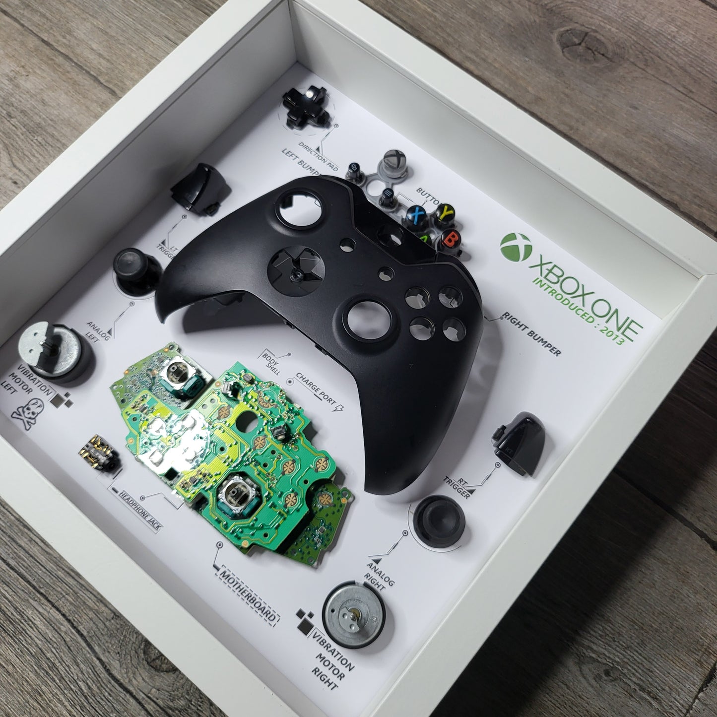 Shadow Box 10x10 with wood frame and polycarbonate glass for wall and Tabletop containing a disassembled controller for Playstation and Nintendo