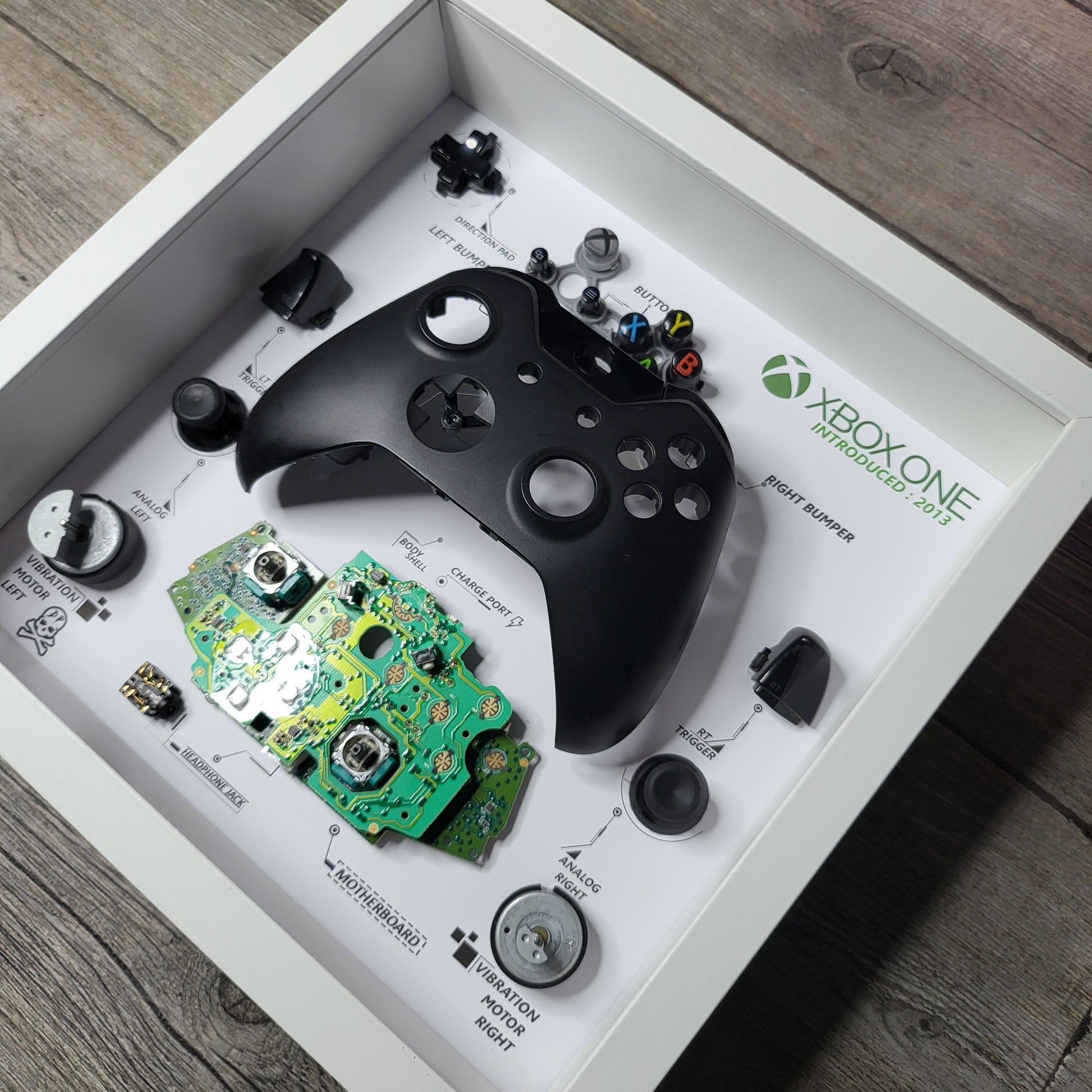 Shadow Box 10x10 with wood frame and polycarbonate glass for wall and Tabletop containing a disassembled controller for Playstation and Nintendo