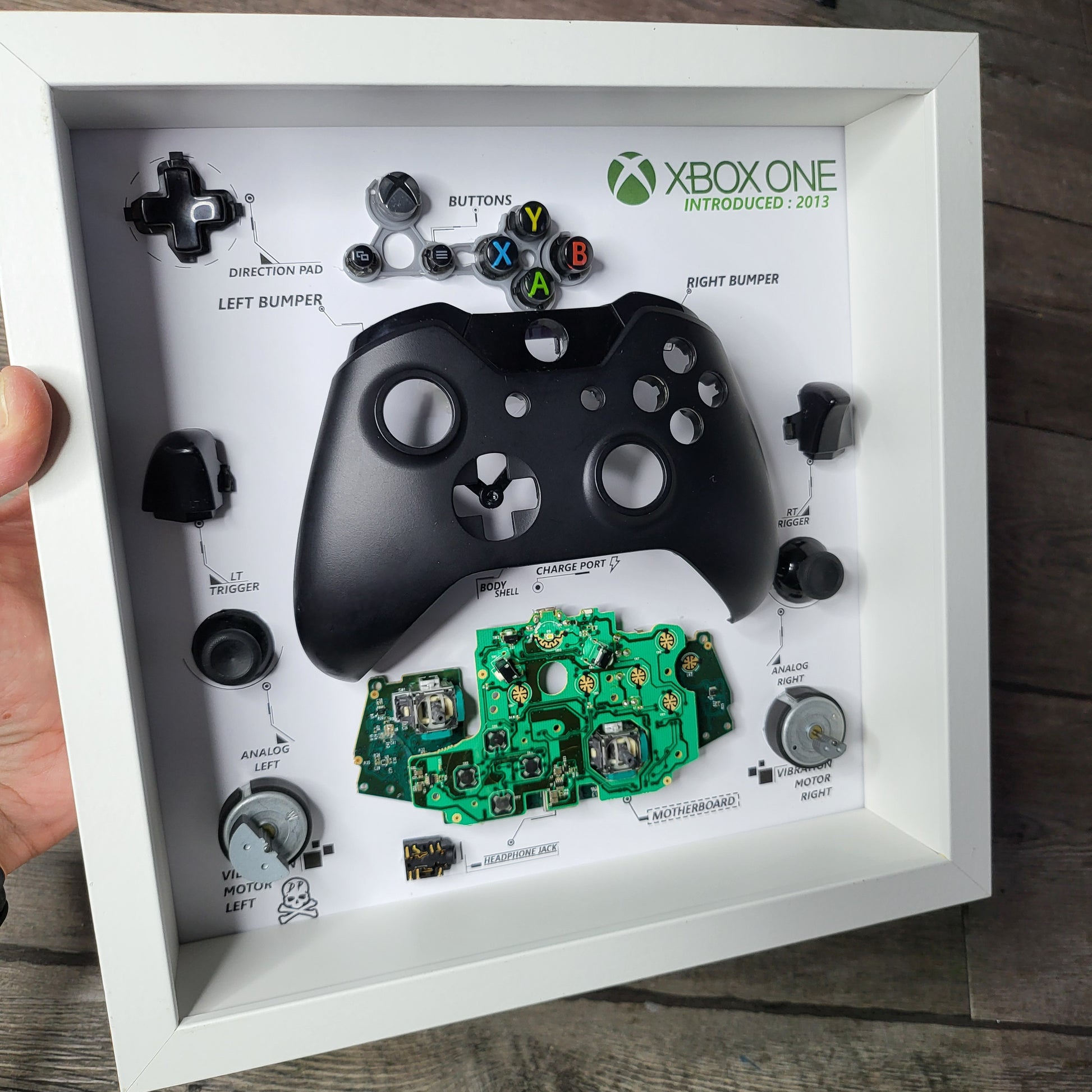 Shadow Box 10x10 with wood frame and polycarbonate glass for wall and Tabletop containing a disassembled controller for Playstation and Nintendo