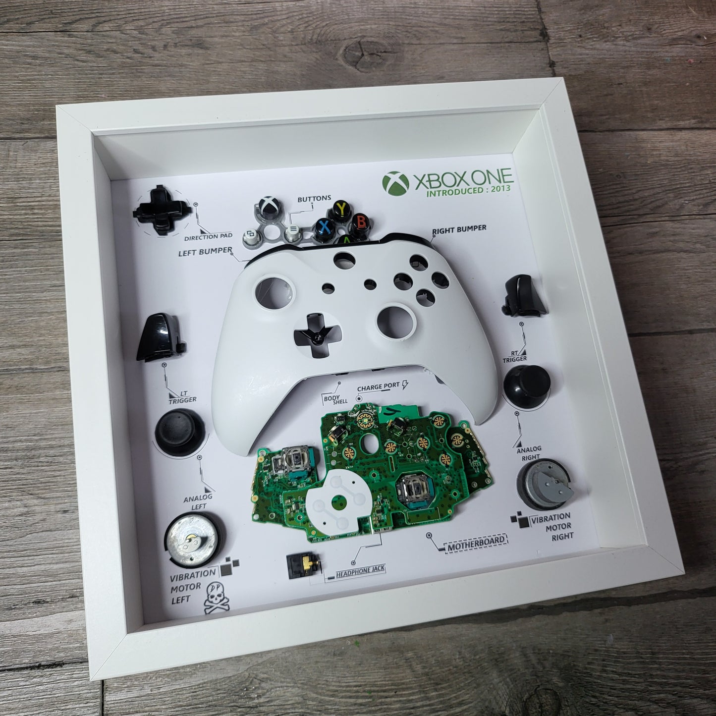 Shadow Box 10x10 with wood frame and polycarbonate glass for wall and Tabletop containing a disassembled controller for Playstation and Nintendo