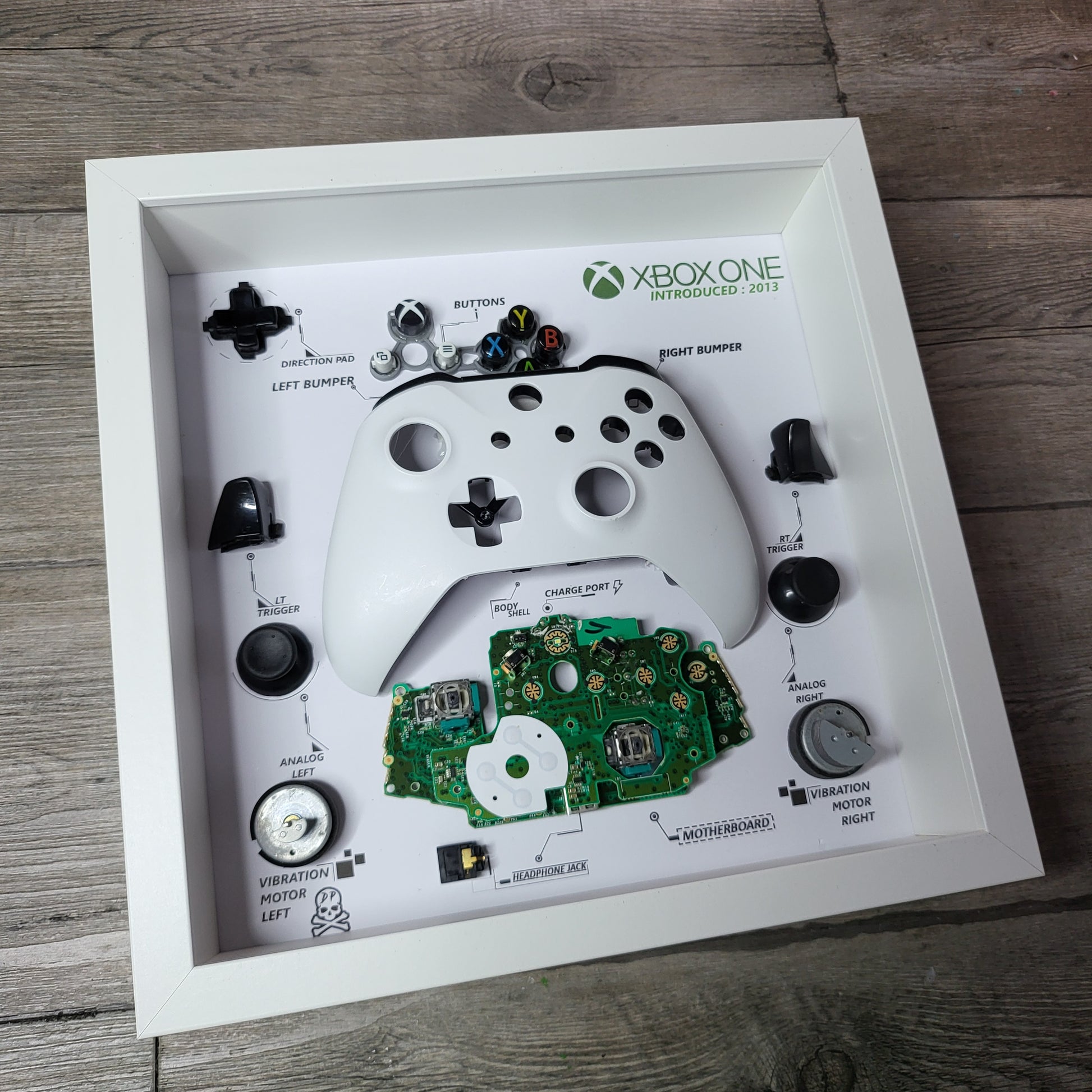 Shadow Box 10x10 with wood frame and polycarbonate glass for wall and Tabletop containing a disassembled controller for Playstation and Nintendo