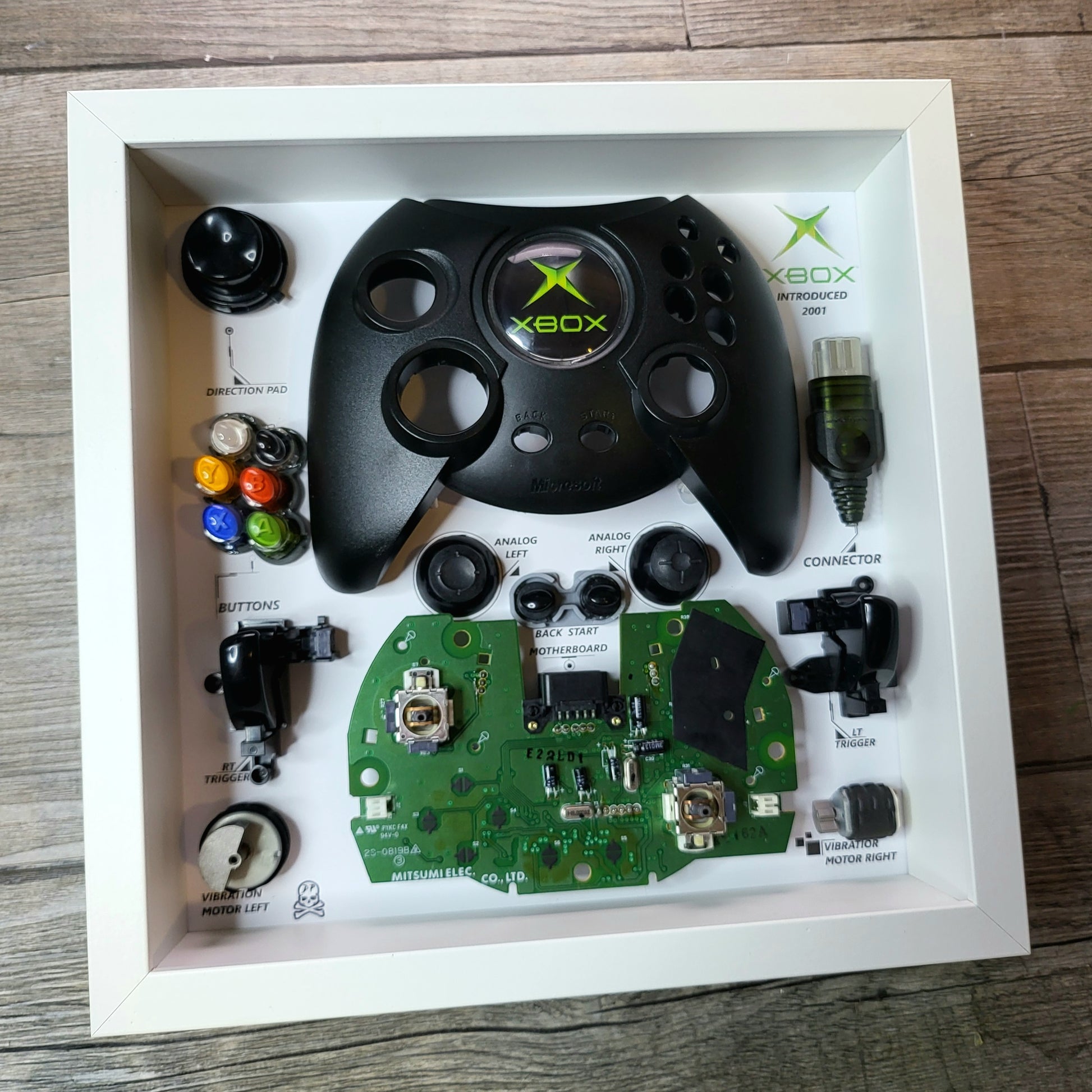 Shadow Box 10x10 with wood frame and polycarbonate glass for wall and Tabletop containing a disassembled controller for Playstation and Nintendo