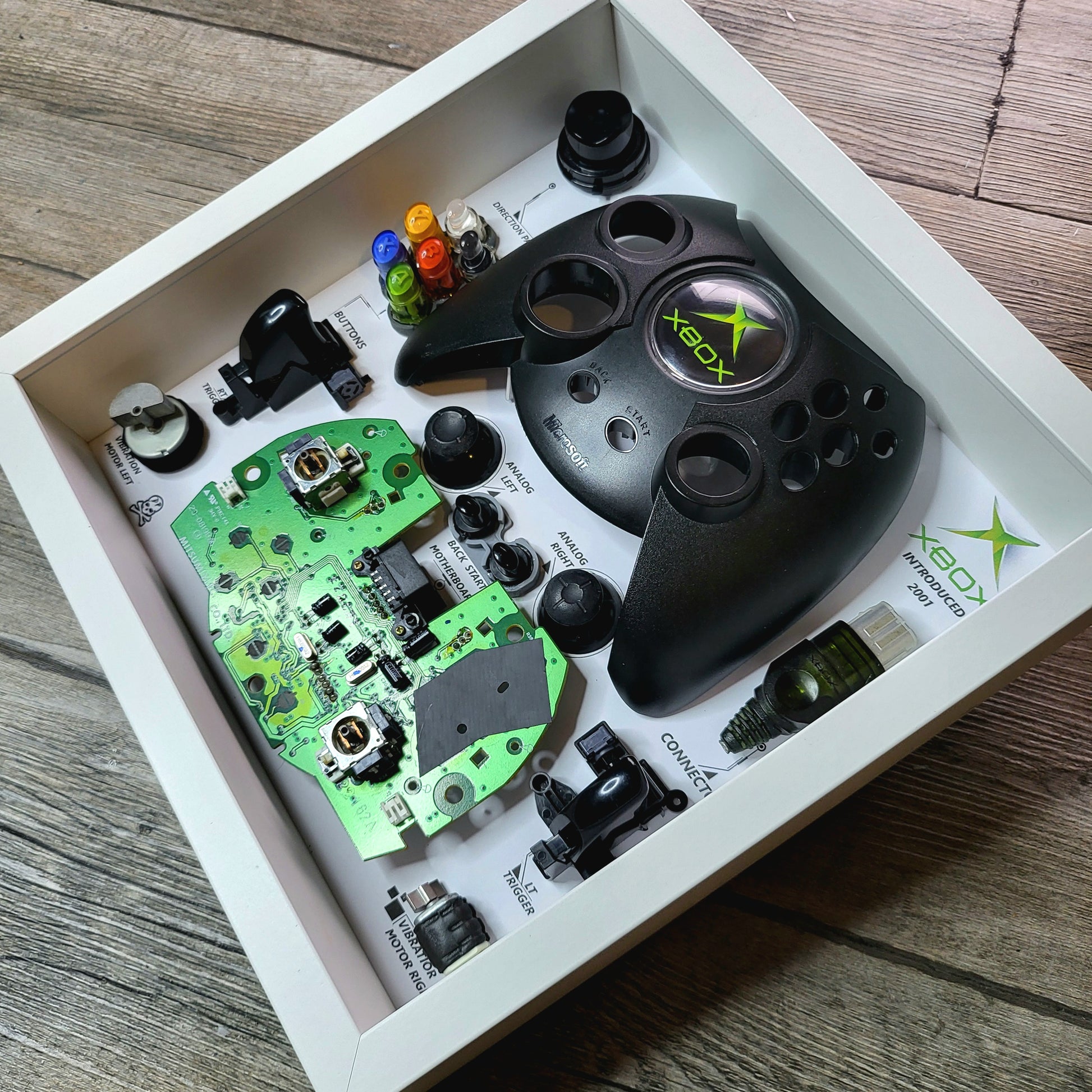 Shadow Box 10x10 with wood frame and polycarbonate glass for wall and Tabletop containing a disassembled controller for Playstation and Nintendo