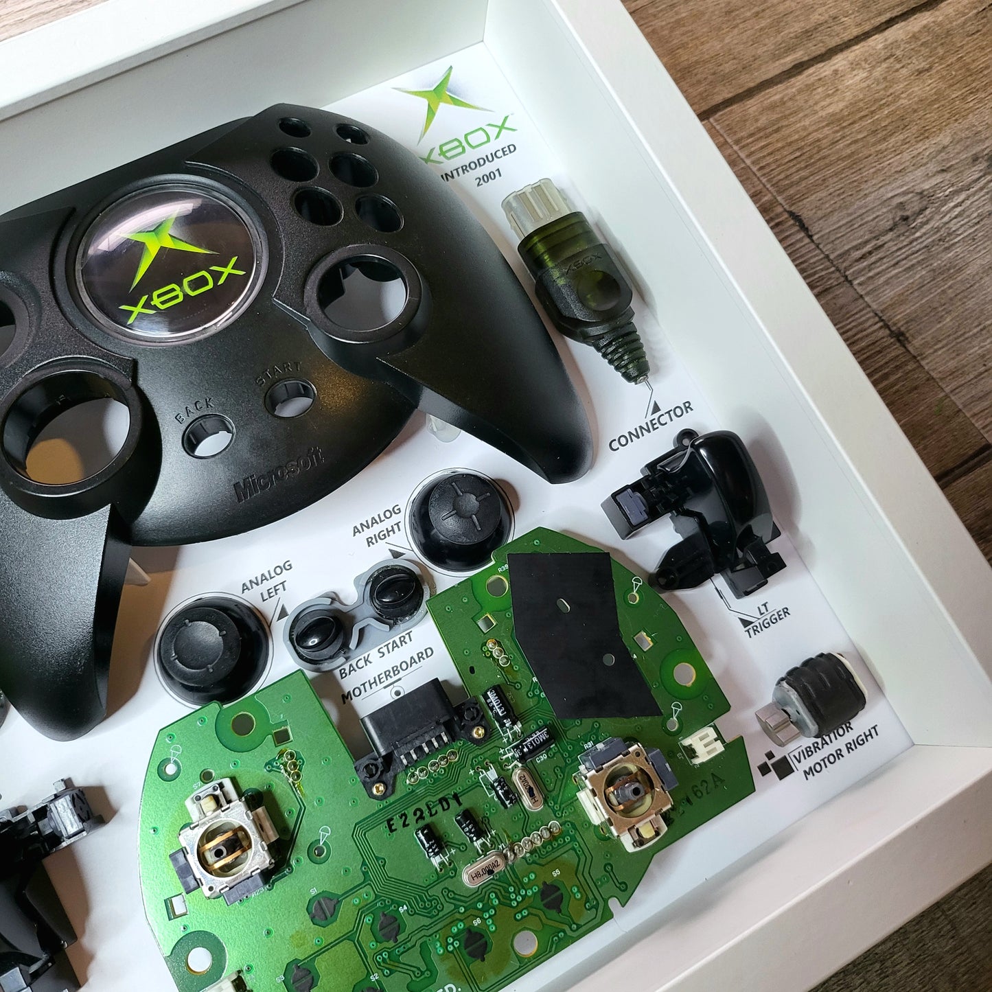 Shadow Box 10x10 with wood frame and polycarbonate glass for wall and Tabletop containing a disassembled controller for Playstation and Nintendo