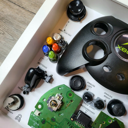 Shadow Box 10x10 with wood frame and polycarbonate glass for wall and Tabletop containing a disassembled controller for Playstation and Nintendo