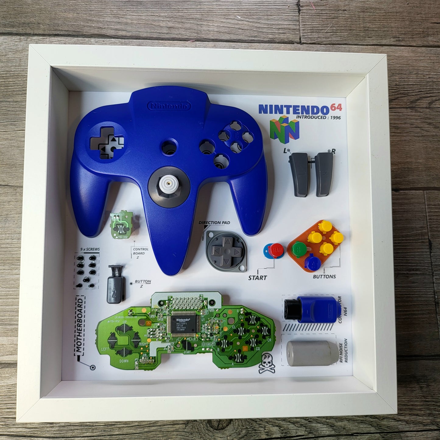 Shadow Box 10x10 with wood frame and polycarbonate glass for wall and Tabletop containing a disassembled controller for Playstation and Nintendo