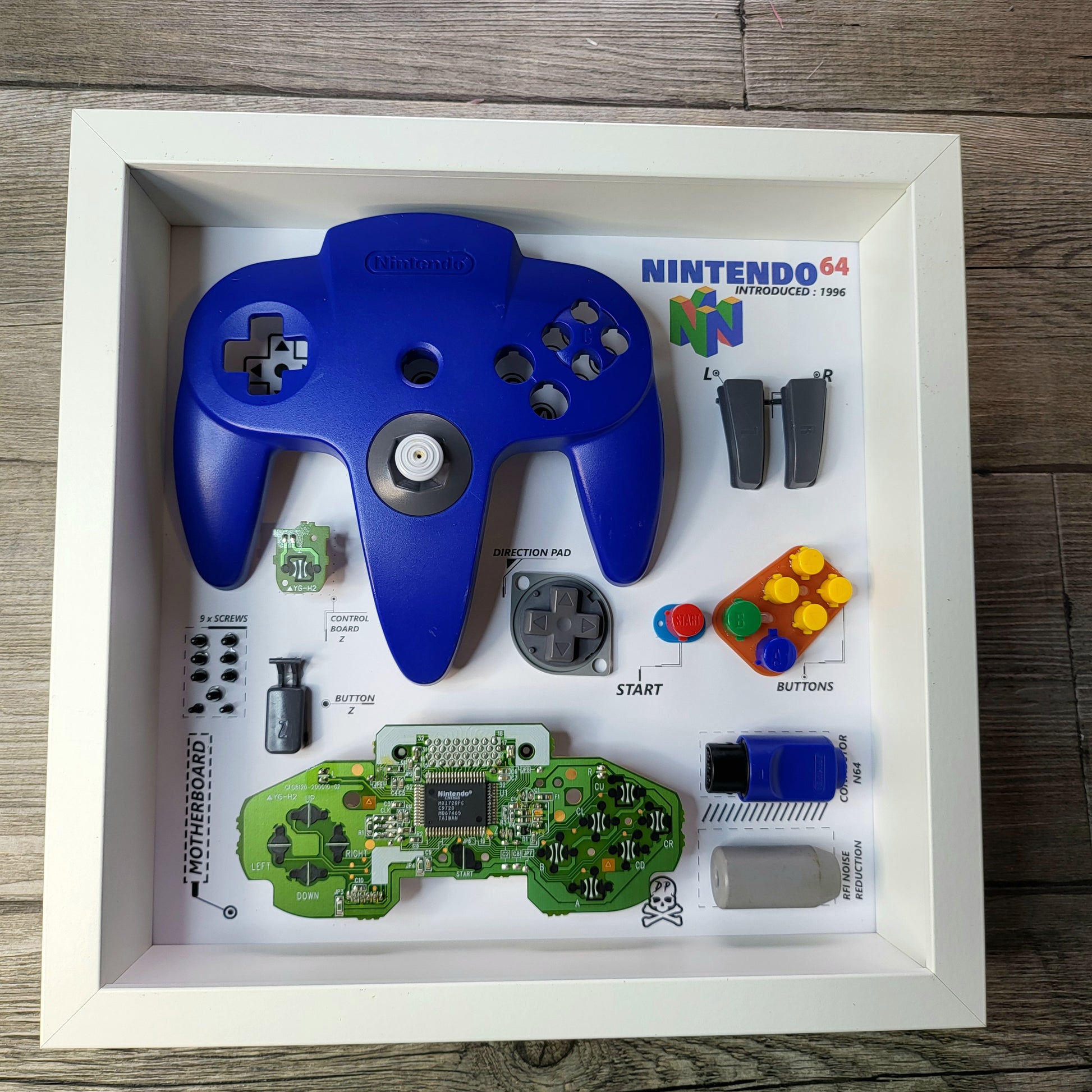 Shadow Box 10x10 with wood frame and polycarbonate glass for wall and Tabletop containing a disassembled controller for Playstation and Nintendo