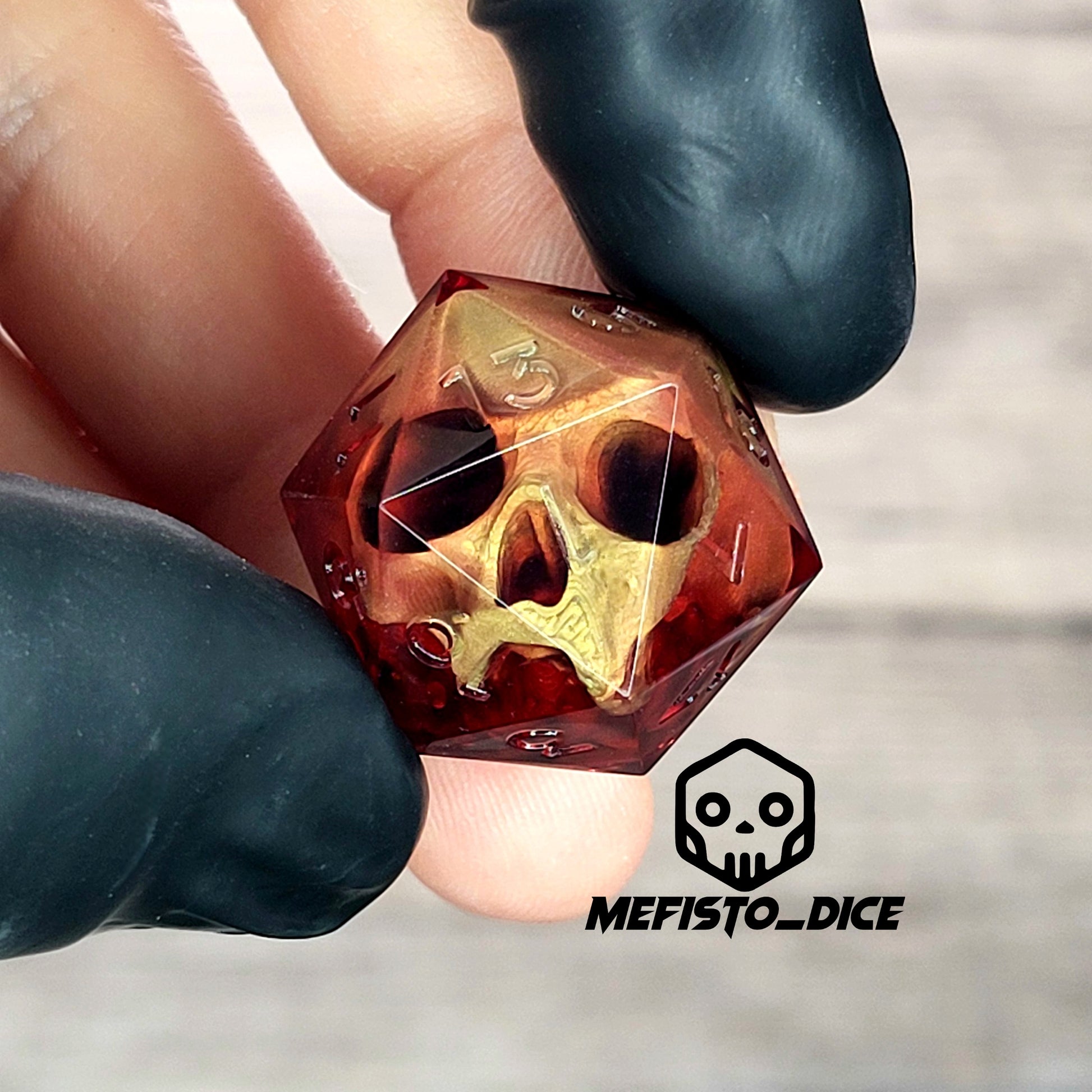 Handmade translucent red resin D20 dice with embedded skull design, held between black-gloved fingers. Gothic tabletop gaming dice with dark fantasy aesthetic for Dungeons & Dragons and RPG players