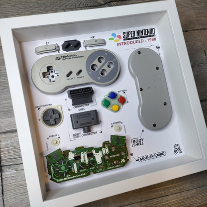 Shadow Box 10x10 with wood frame and polycarbonate glass for wall and Tabletop containing a disassembled controller for Playstation and Nintendo