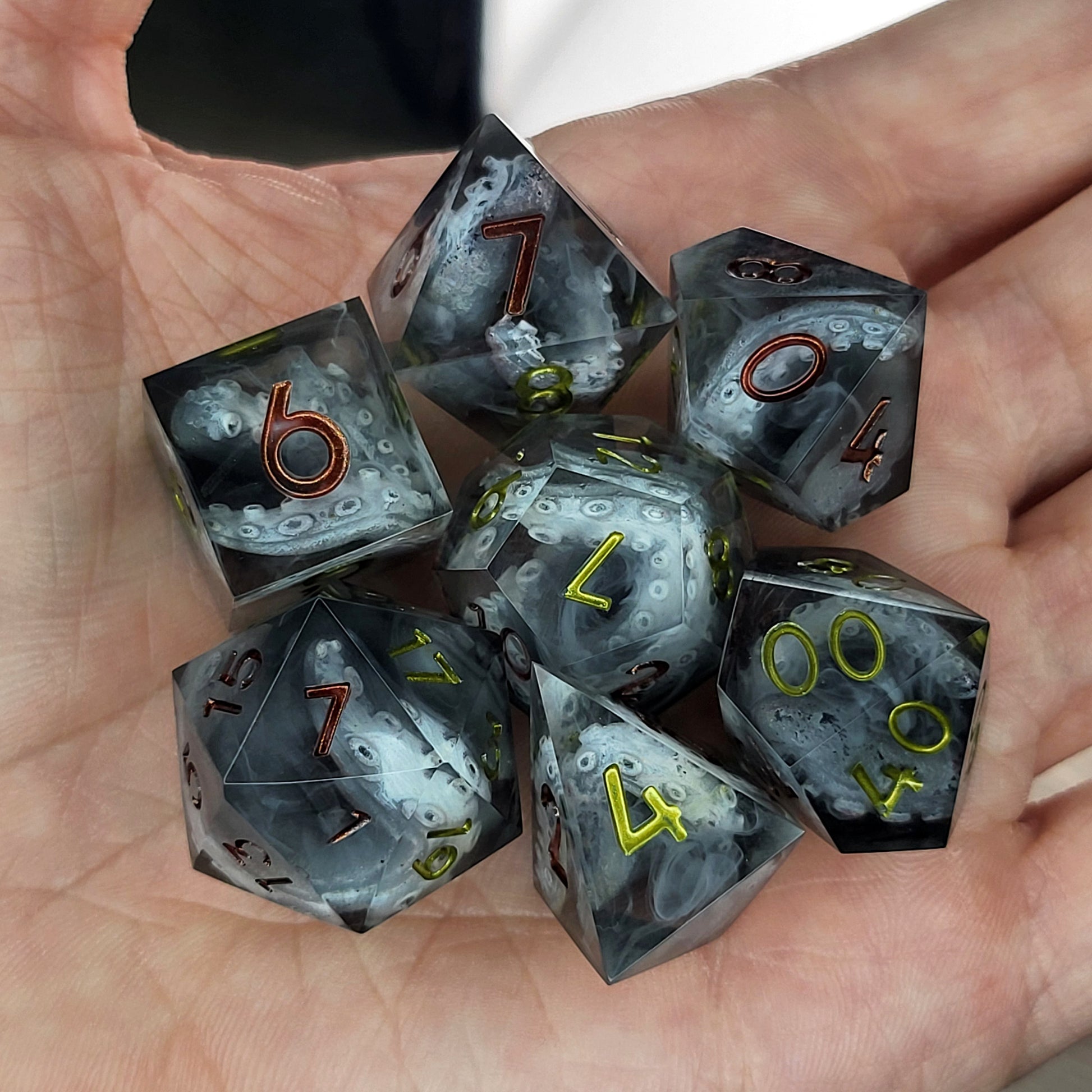 Black and gray resin DnD dice set with detailed tentacle patterns inside and metallic red and yellow numbers