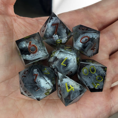 Black and gray resin DnD dice set with detailed tentacle patterns inside and metallic red and yellow numbers