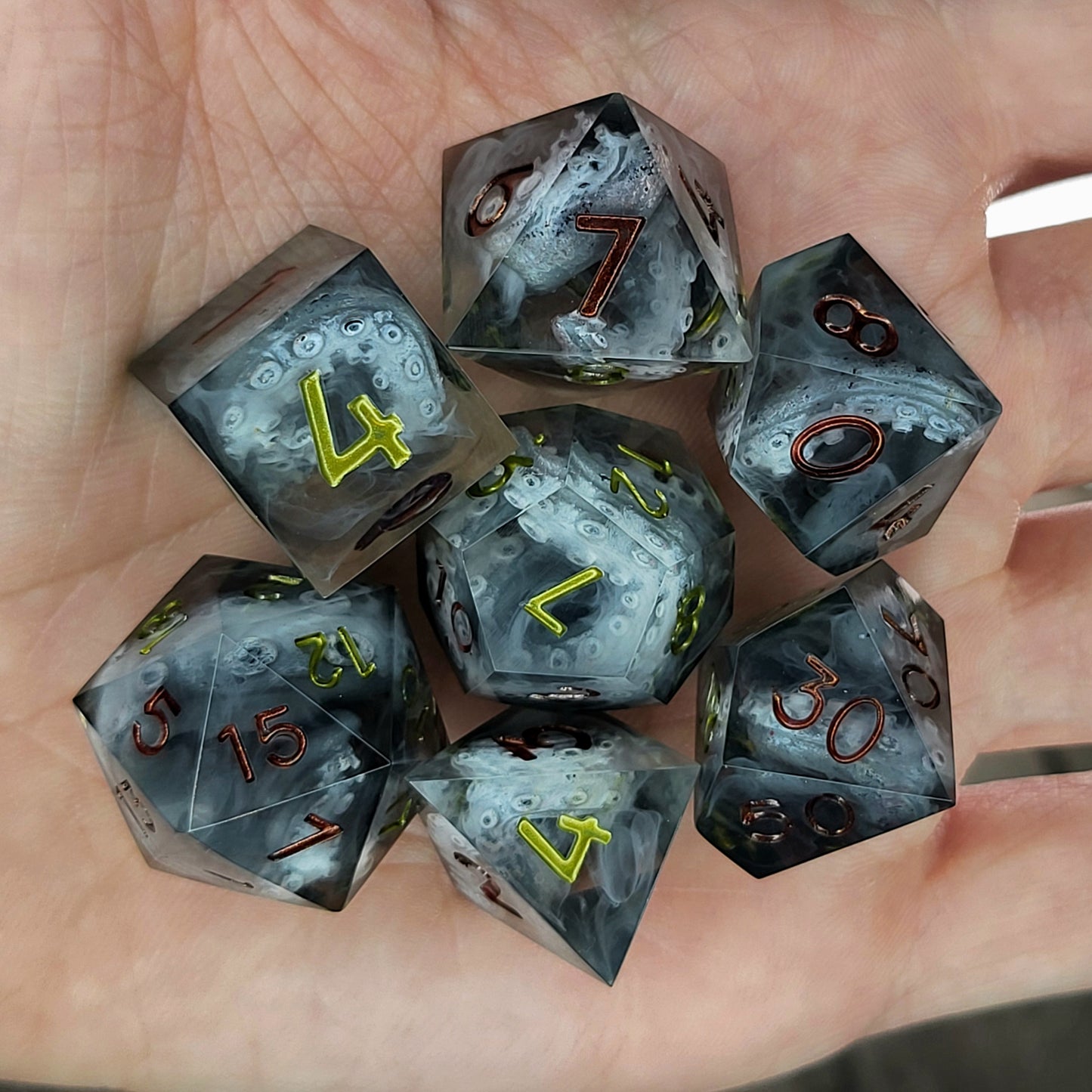 Black and gray resin DnD dice set with detailed tentacle patterns inside and metallic red and yellow numbers
