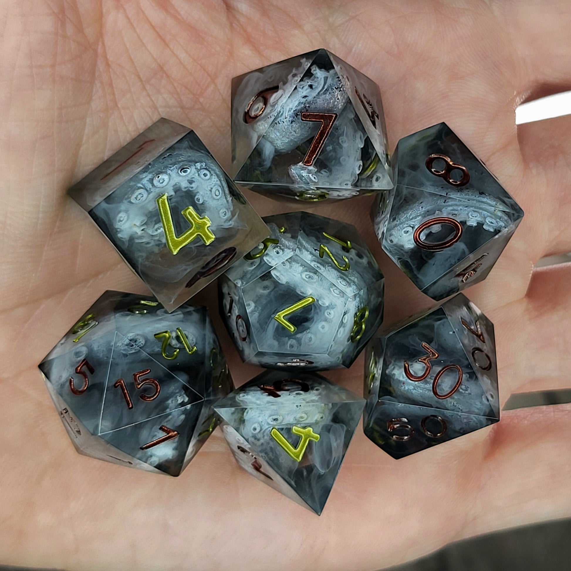 Black and gray resin DnD dice set with detailed tentacle patterns inside and metallic red and yellow numbers
