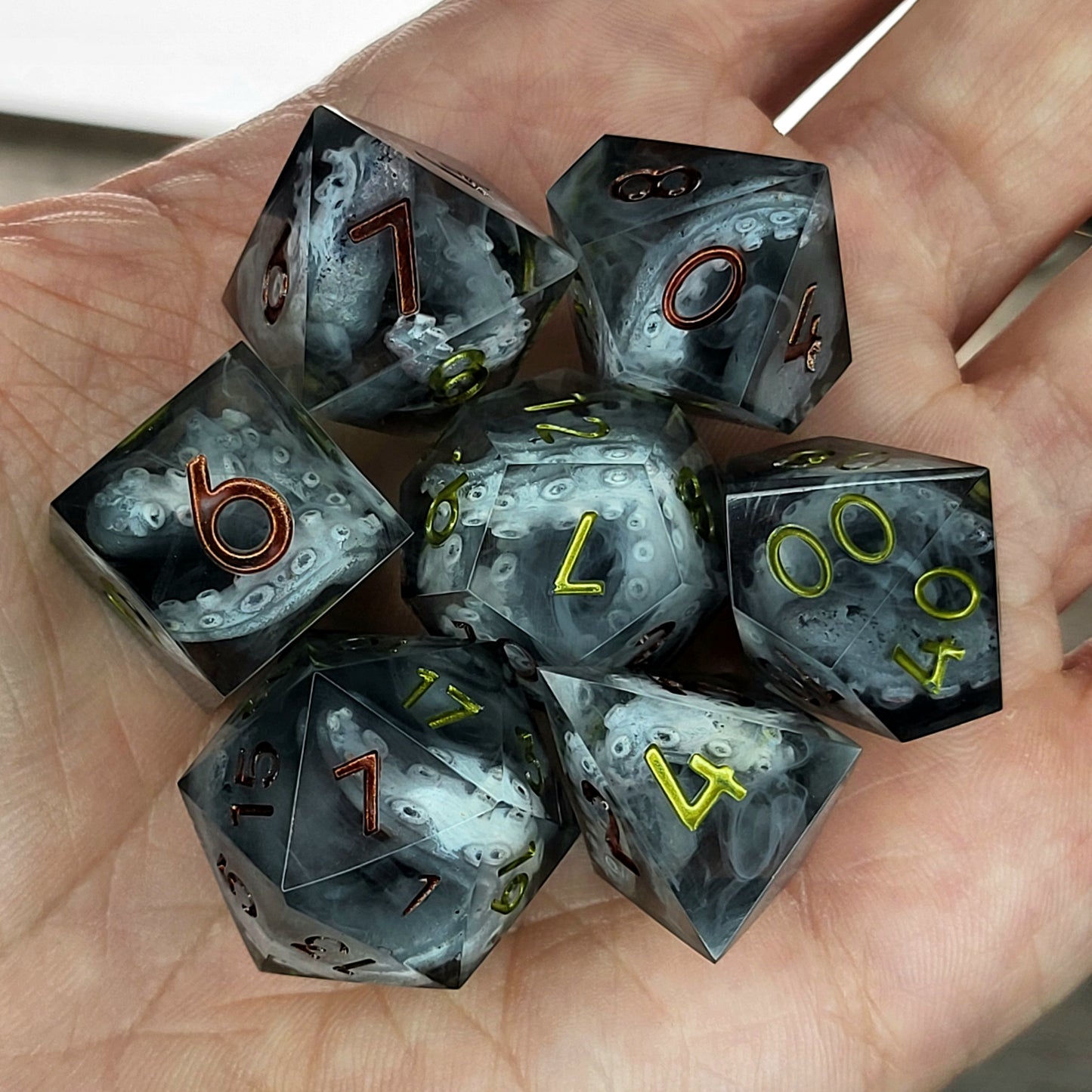 Black and gray resin DnD dice set with detailed tentacle patterns inside and metallic red and yellow numbers