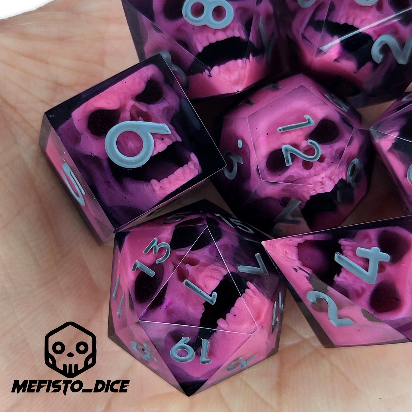 Close-up of black resin dice with pink undead zombie skulls and grey numbers, handcrafted by Mefisto_Dice.