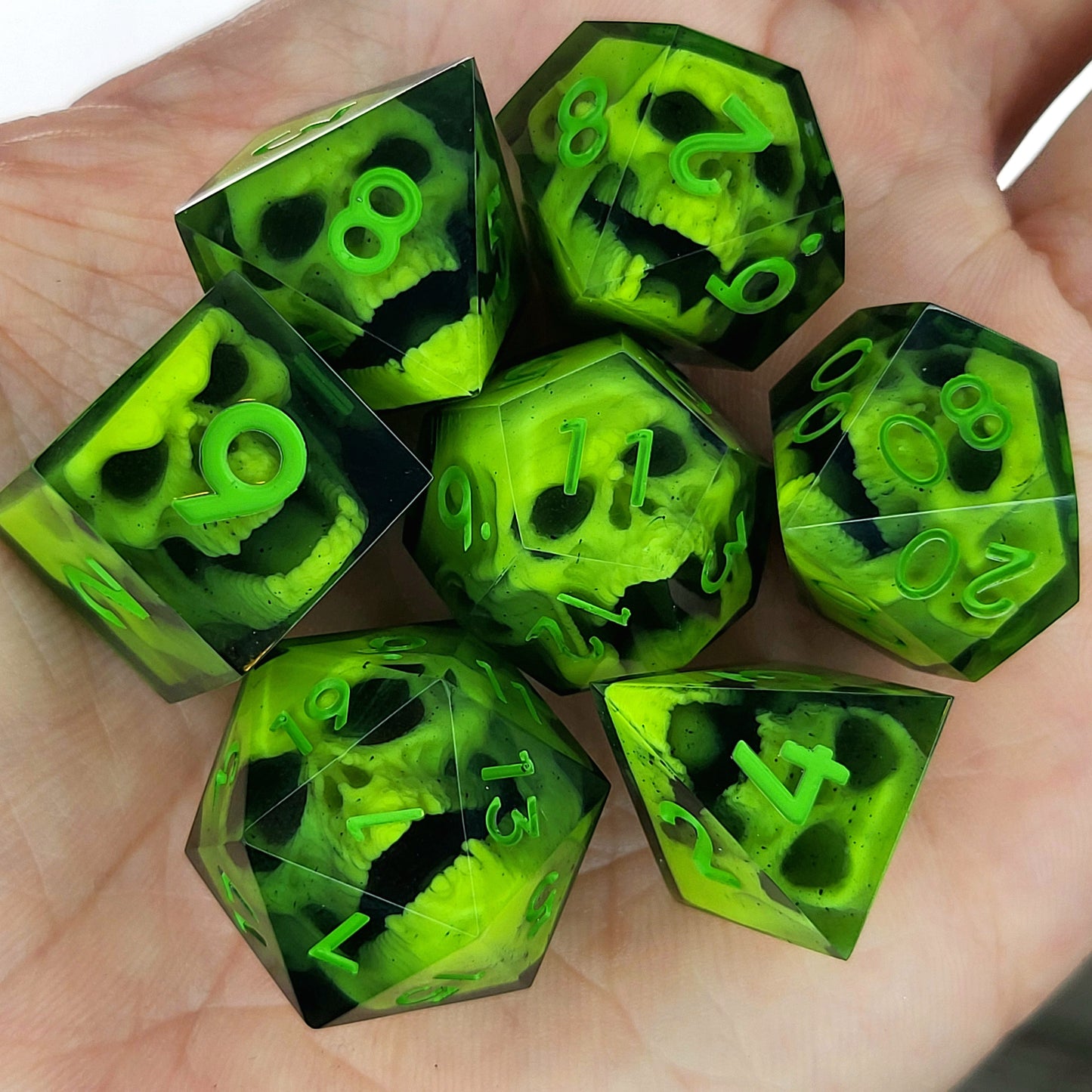 Close-up of black resin dice with neon-green undead zombie skulls and bright green numbers, handcrafted by Mefisto_Dice.