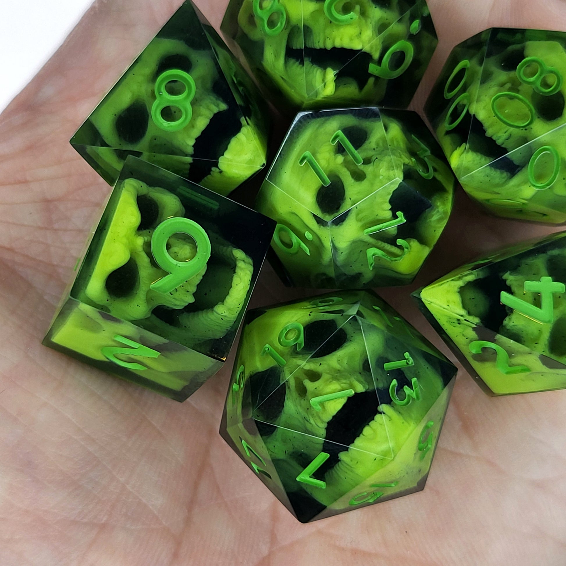 Close-up of black resin dice with neon-green undead zombie skulls and bright green numbers, handcrafted by Mefisto_Dice.