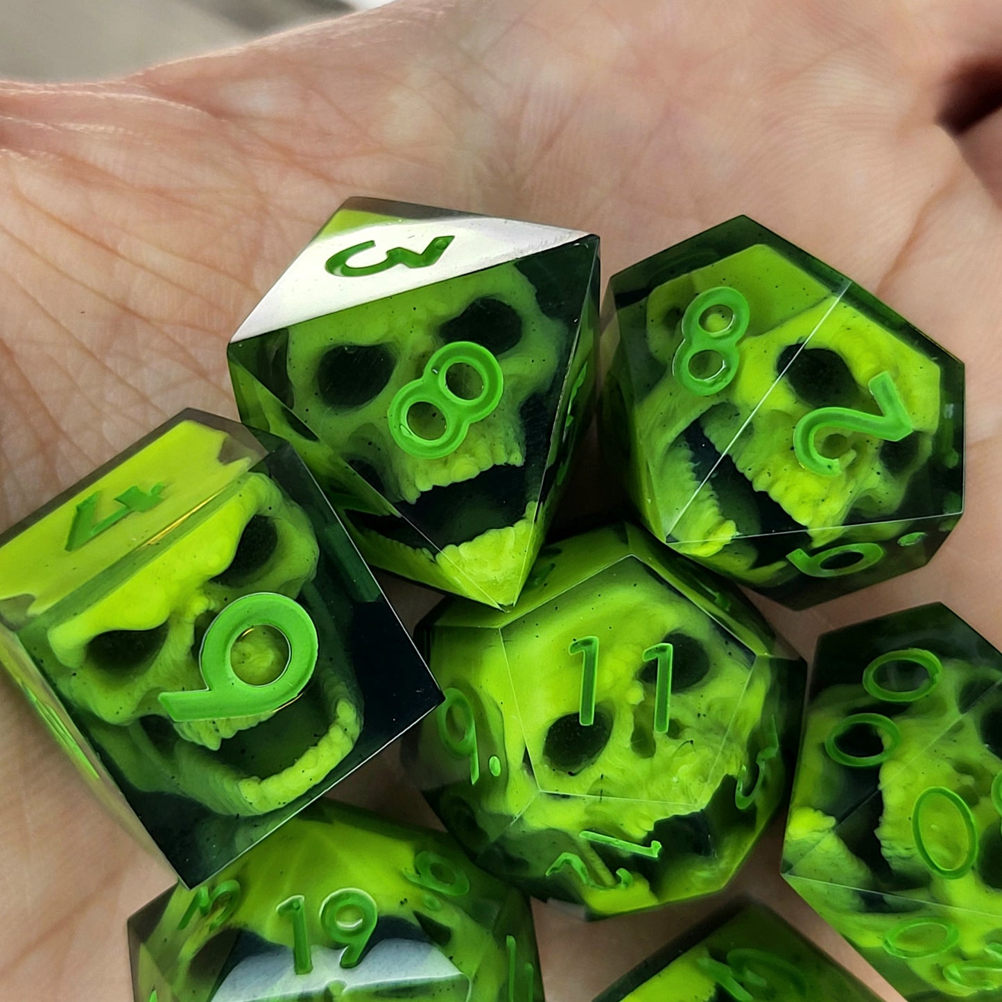 Close-up of black resin dice with neon-green undead zombie skulls and bright green numbers, handcrafted by Mefisto_Dice.