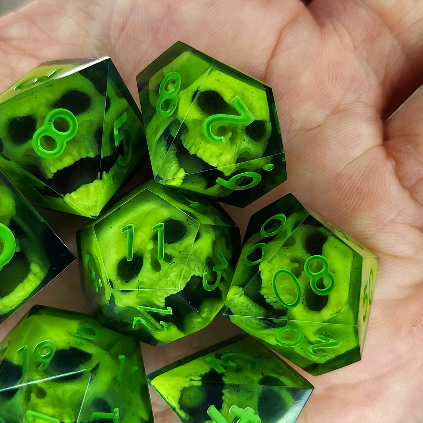 Close-up of black resin dice with neon-green undead zombie skulls and bright green numbers, handcrafted by Mefisto_Dice.
