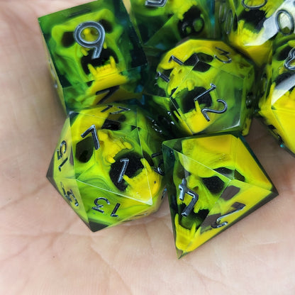 Blue resin DnD dice set with bright yellow skulls inside and silver engraved numbers