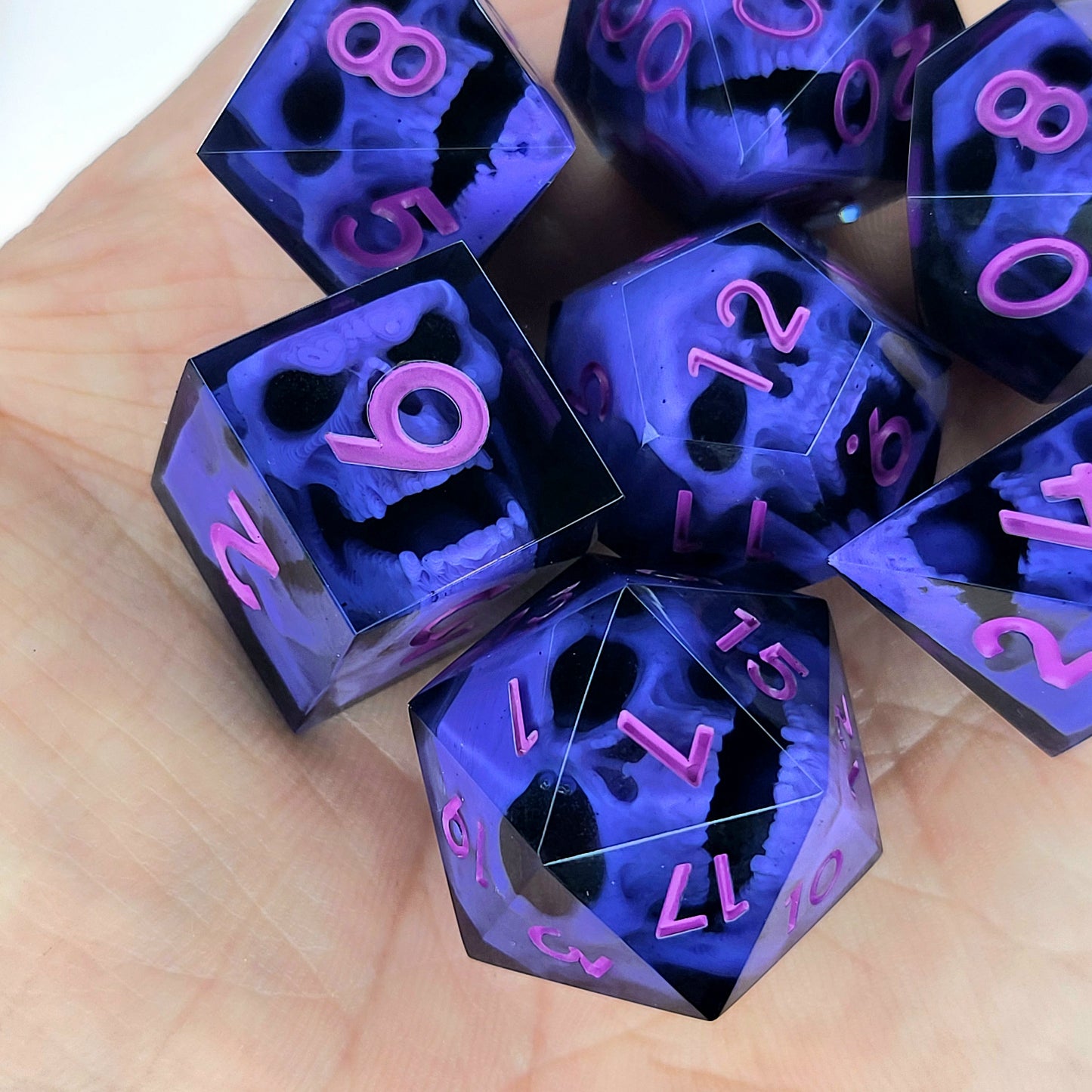 Close-up of black resin dice with purple zombie skulls inside and pink numbers, handcrafted by Mefisto_Dice.