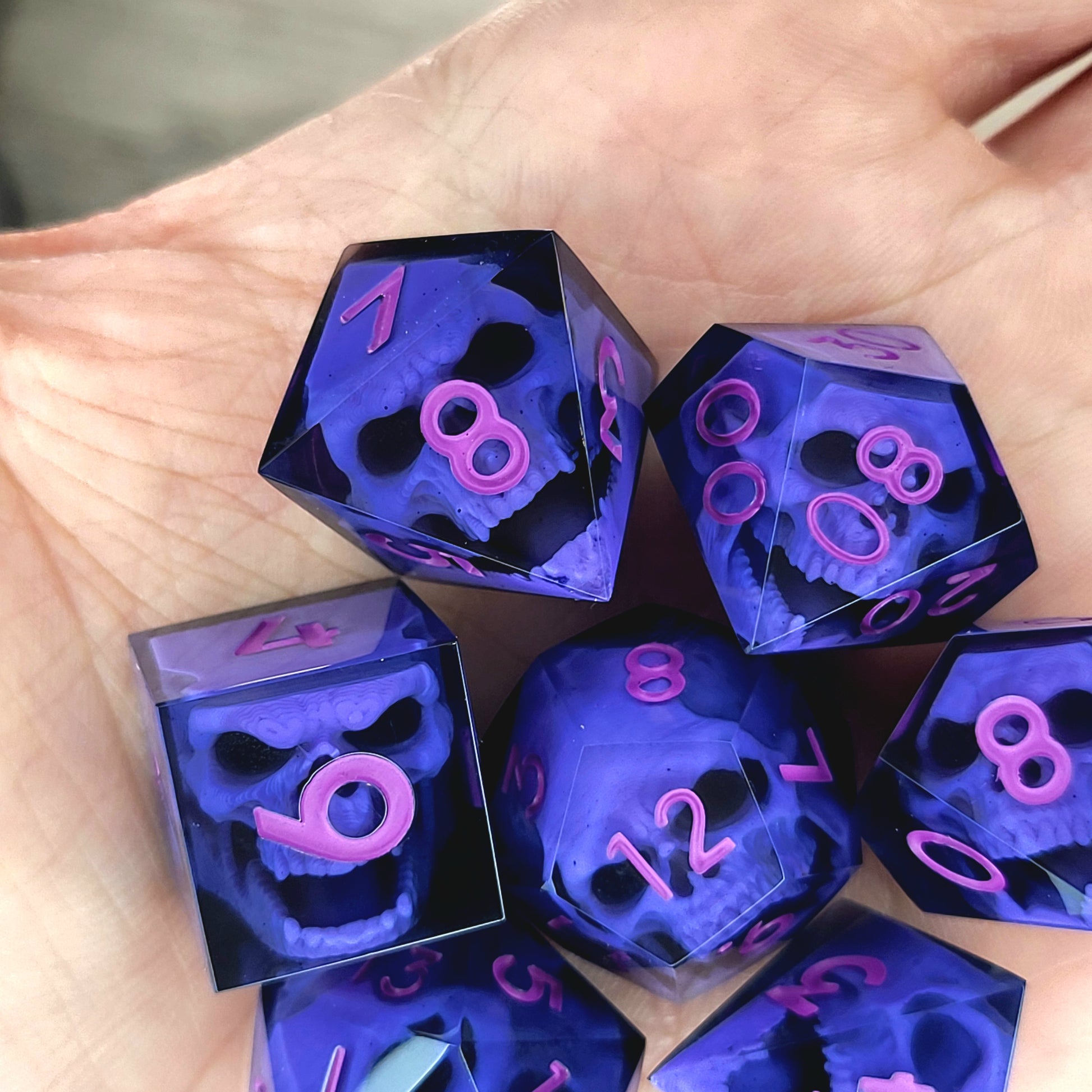 Close-up of black resin dice with purple zombie skulls inside and pink numbers, handcrafted by Mefisto_Dice.