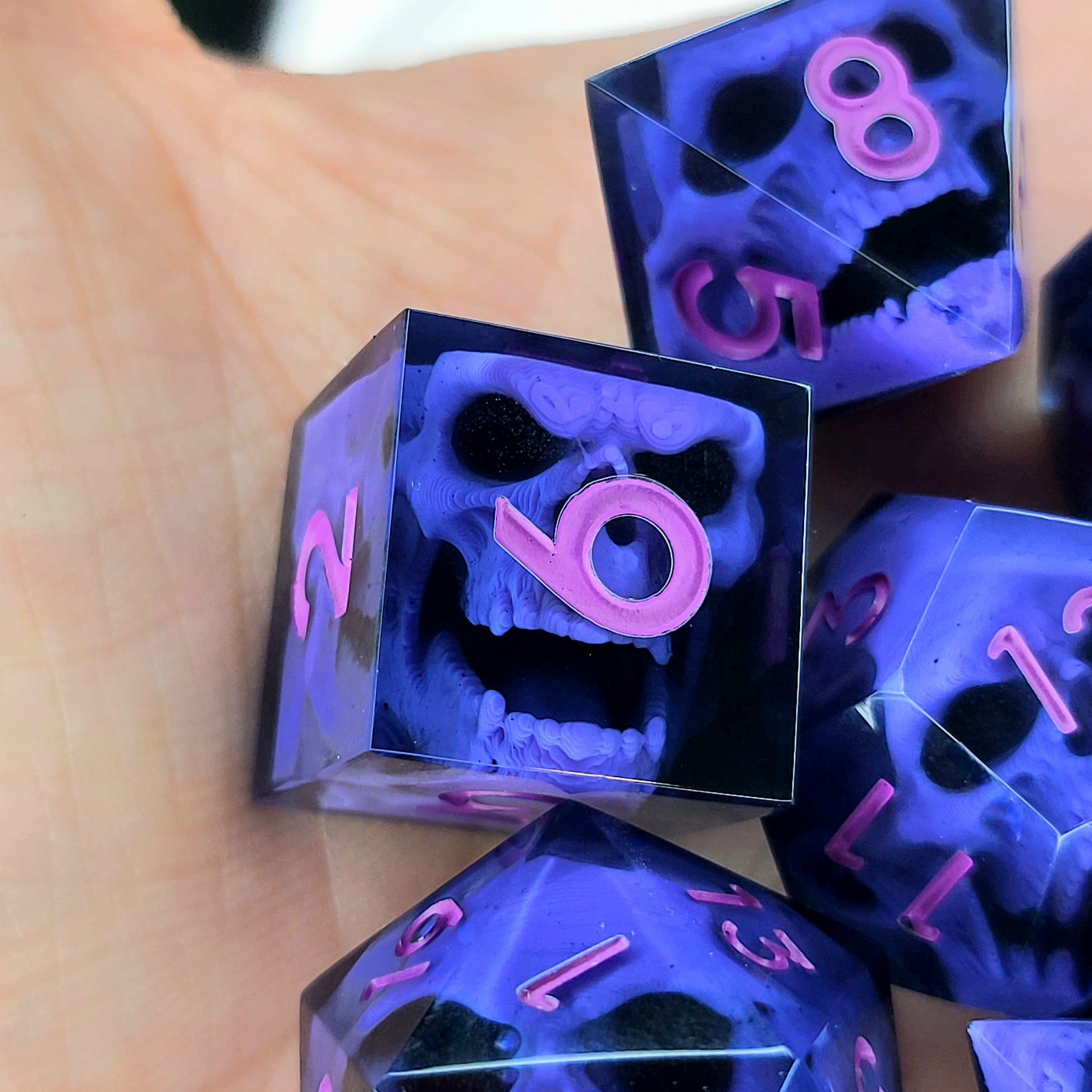 Close-up of black resin dice with purple zombie skulls inside and pink numbers, handcrafted by Mefisto_Dice.