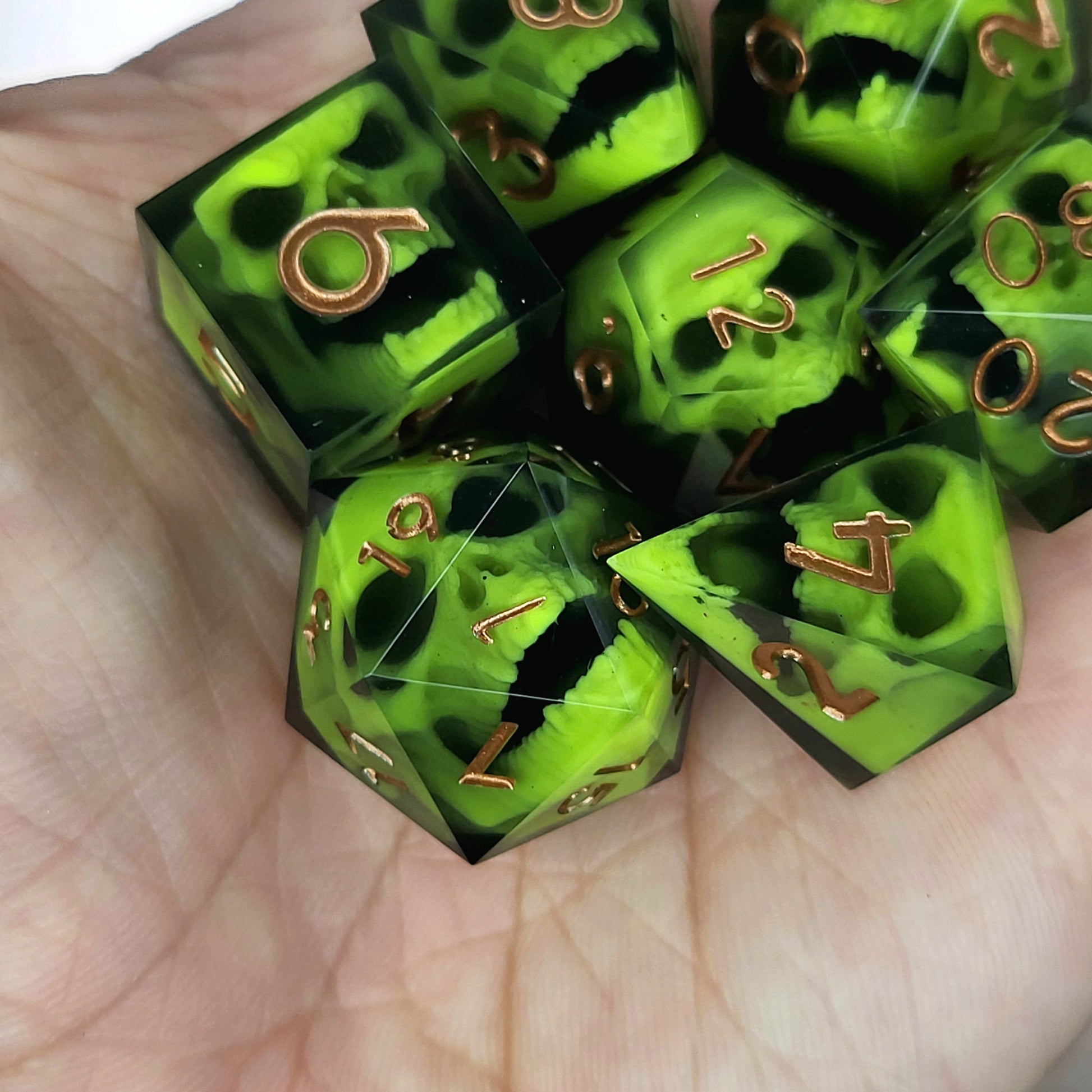 Black resin dice set featuring neon green undead skulls and metallic bronze numbers, handcrafted RPG dice for DnD and tabletop fantasy games