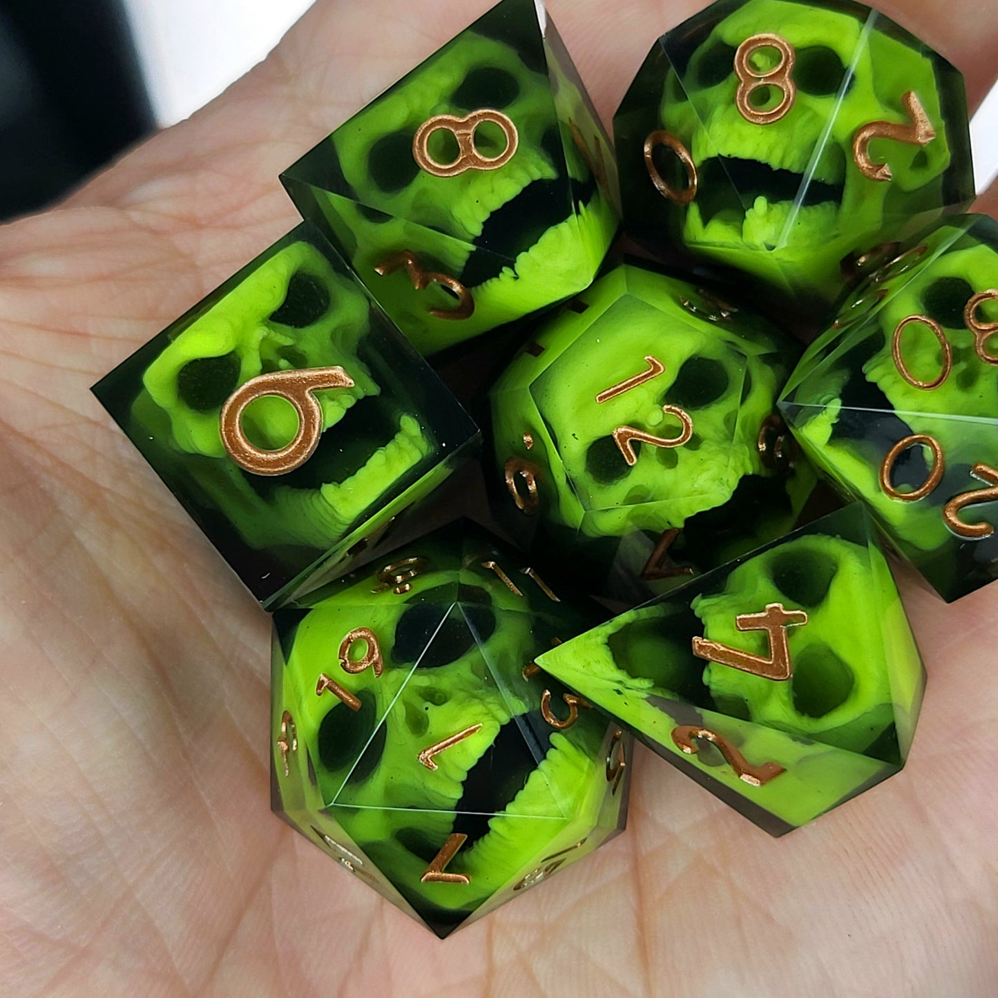 Black resin dice set featuring neon green undead skulls and metallic bronze numbers, handcrafted RPG dice for DnD and tabletop fantasy games