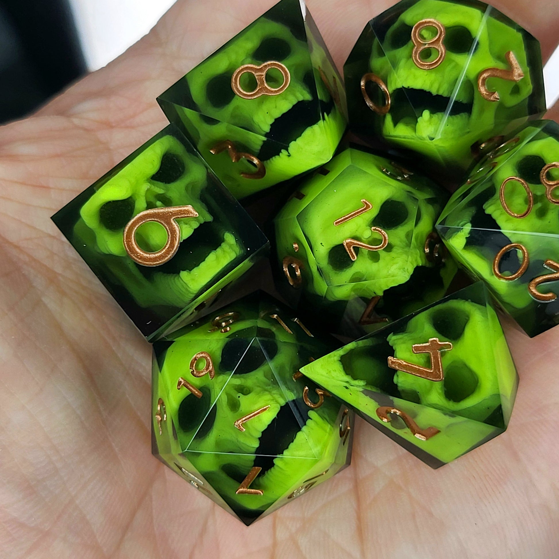 Black resin dice set featuring neon green undead skulls and metallic bronze numbers, handcrafted RPG dice for DnD and tabletop fantasy games