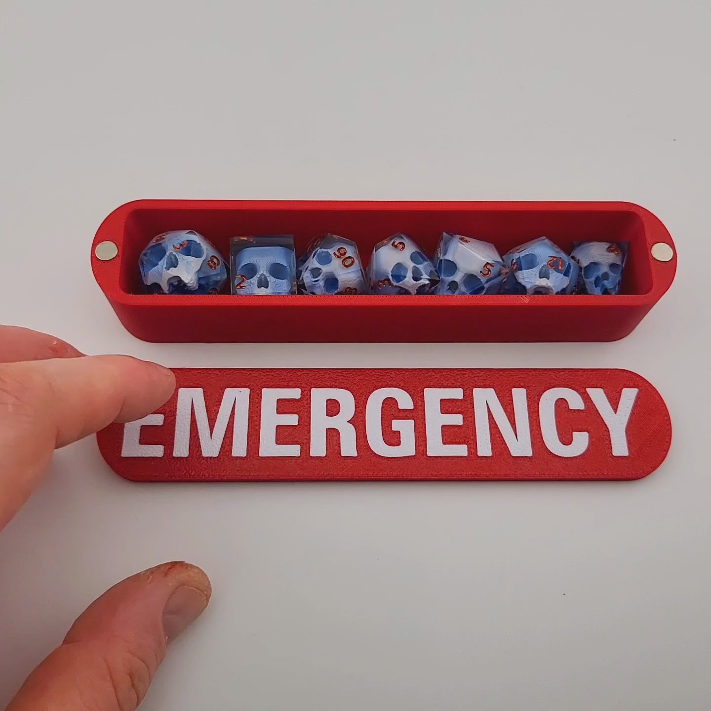 dice box white and red with the word emergency printed on it for dnd and dungeons and dragons games