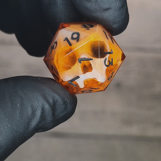 This is a single set of one D20 DnD die with a white skull inside , orange resin and black numbers