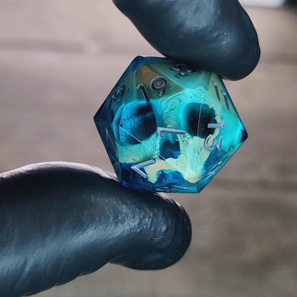 This is a single set of one D20 DnD die with a light yellow skull inside , blue resin and grey numbers