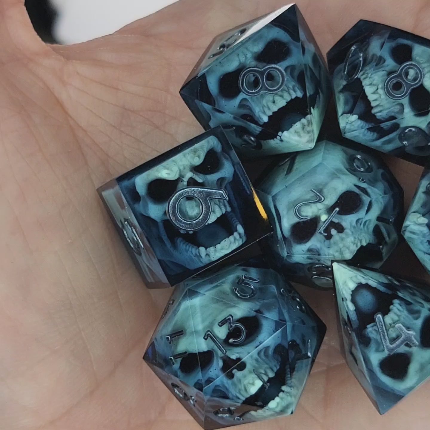 Close-up of black resin dice with mint-green undead zombie skulls and dark metallic silver numbers, handcrafted by Mefisto_Dice.