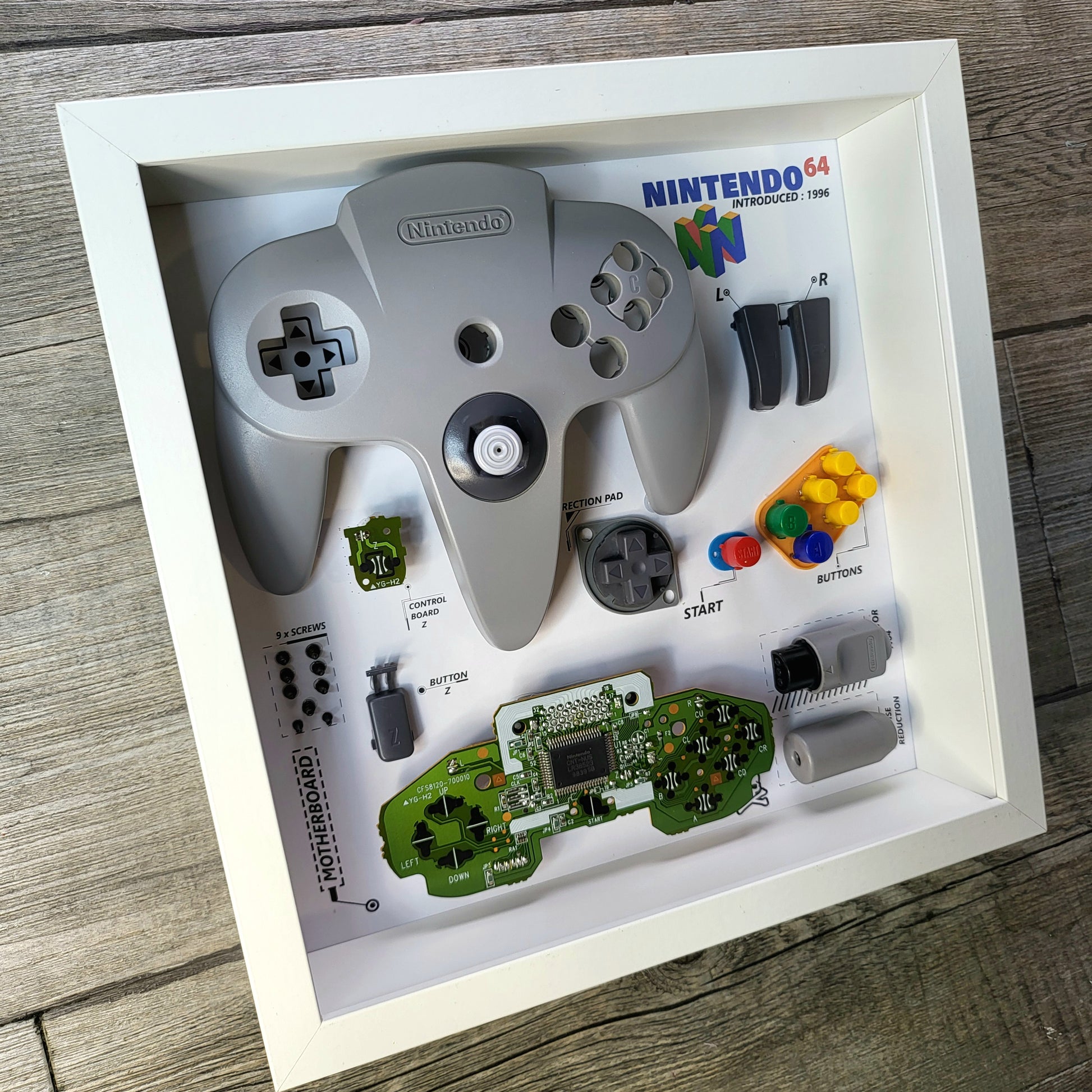 Shadow Box 10x10 with wood frame and polycarbonate glass for wall and Tabletop containing a disassembled controller for Playstation and Nintendo
