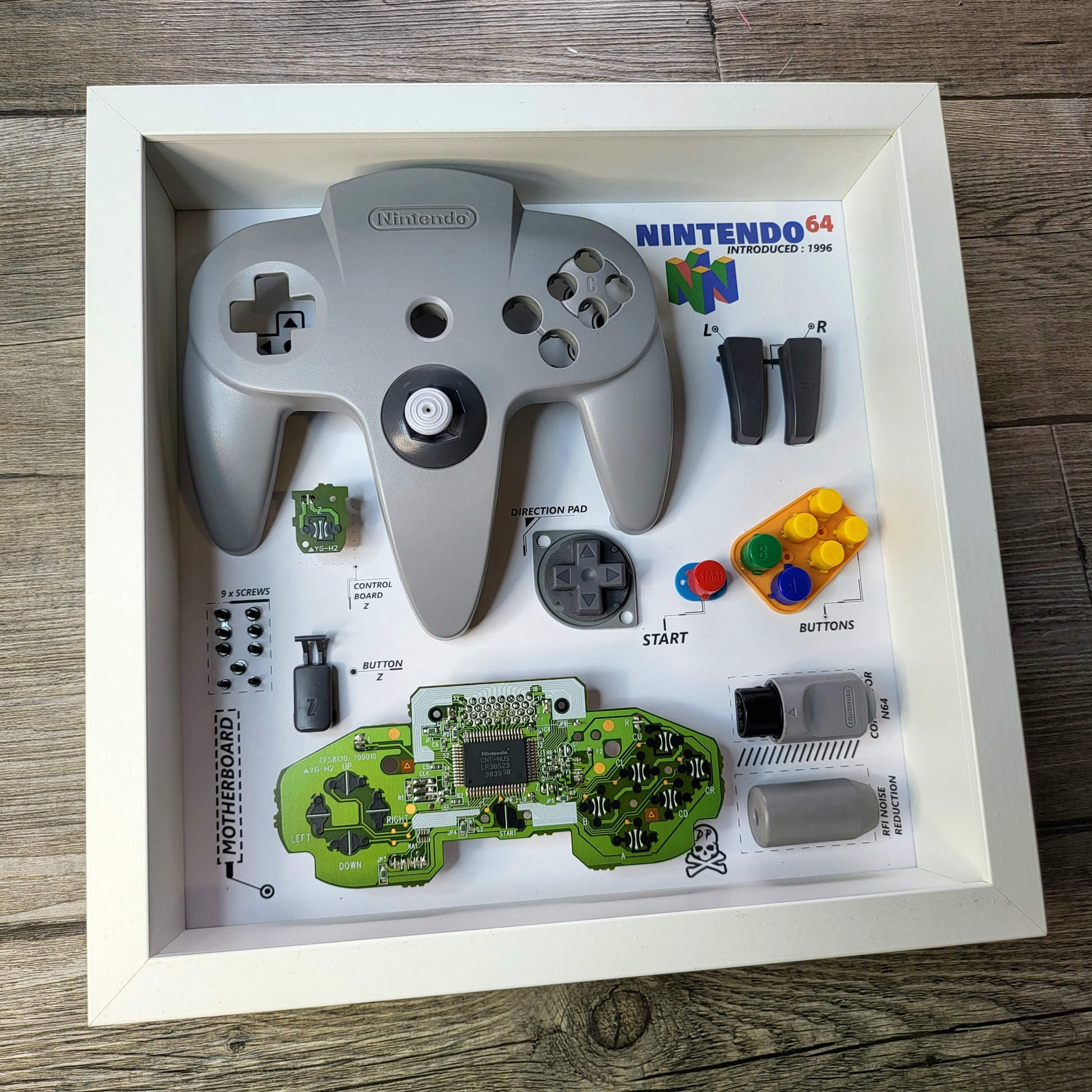 Shadow Box 10x10 with wood frame and polycarbonate glass for wall and Tabletop containing a disassembled controller for Playstation and Nintendo