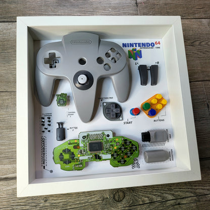 Shadow Box 10x10 with wood frame and polycarbonate glass for wall and Tabletop containing a disassembled controller for Playstation and Nintendo