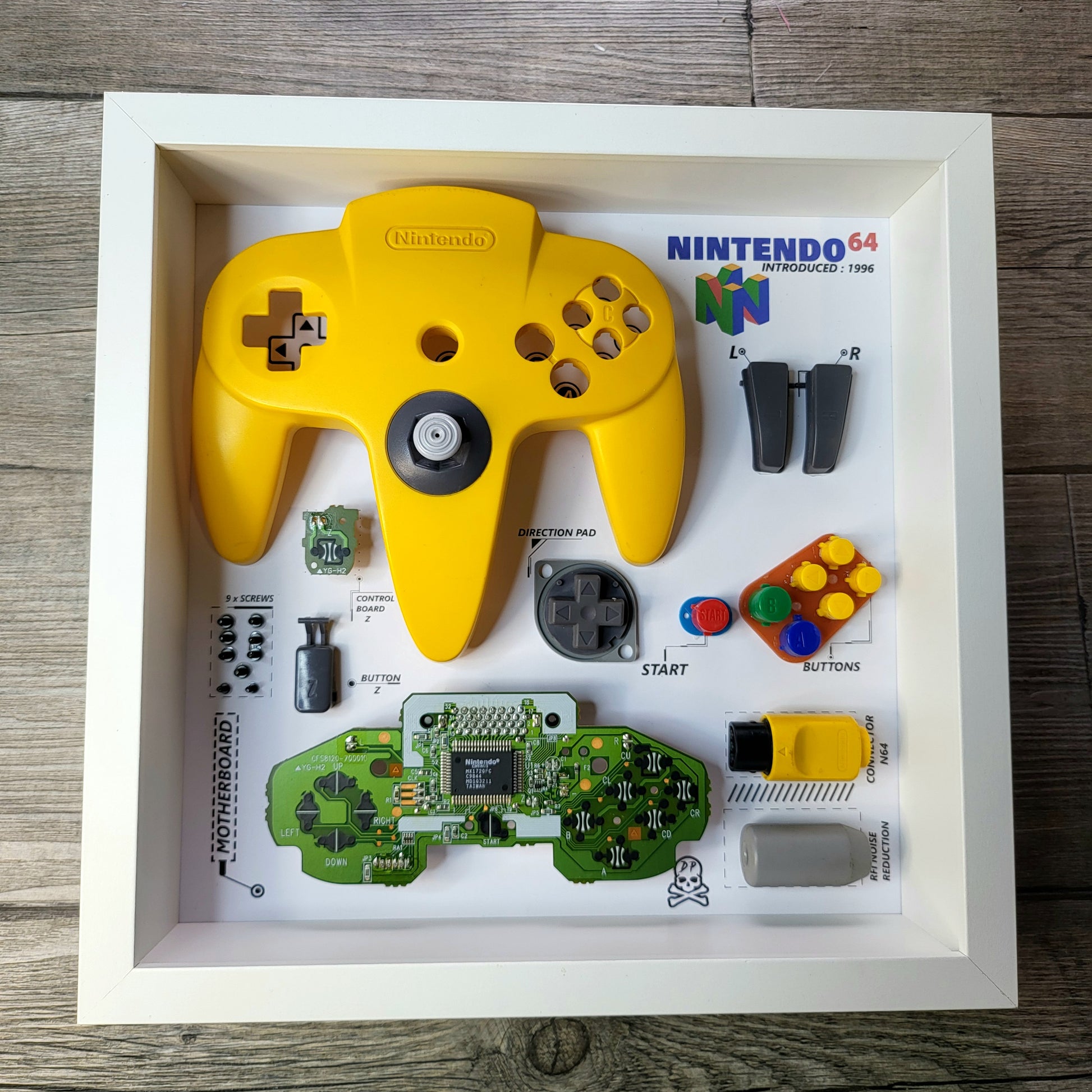 Shadow Box 10x10 with wood frame and polycarbonate glass for wall and Tabletop containing a disassembled controller for Playstation and Nintendo